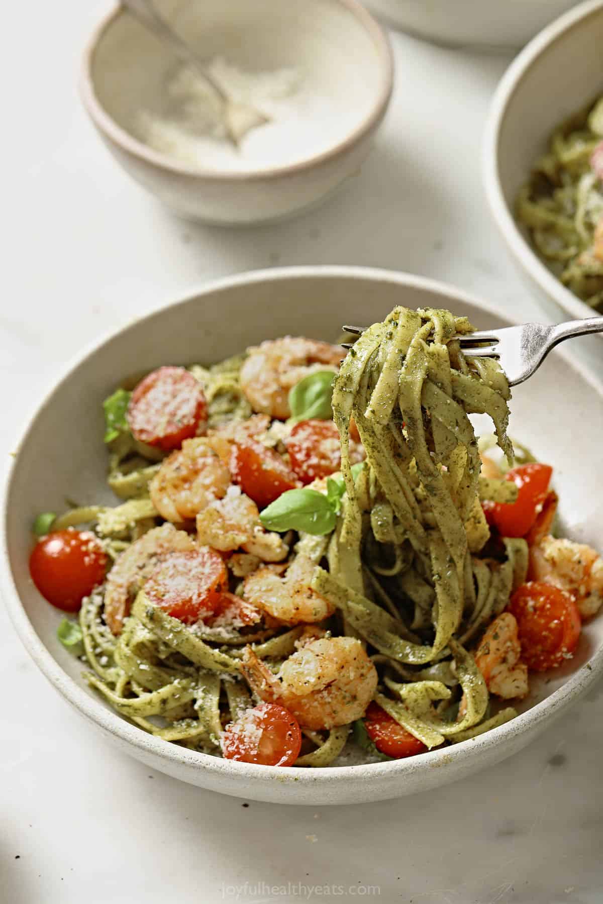Picking up pesto fettuccine with a fork.