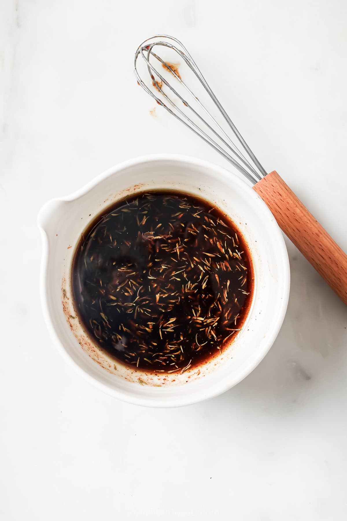 Overhead view of balsamic vinaigrette in small bowl with whisk