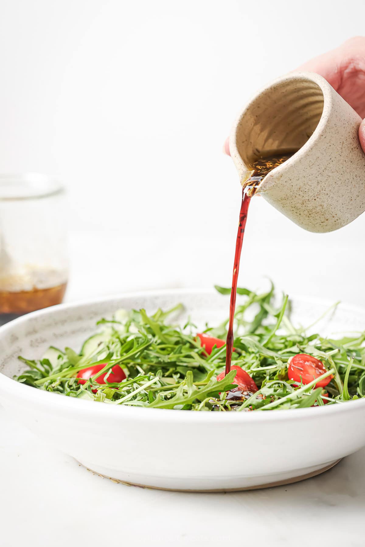 Pouring balsamic vinaigrette into salad