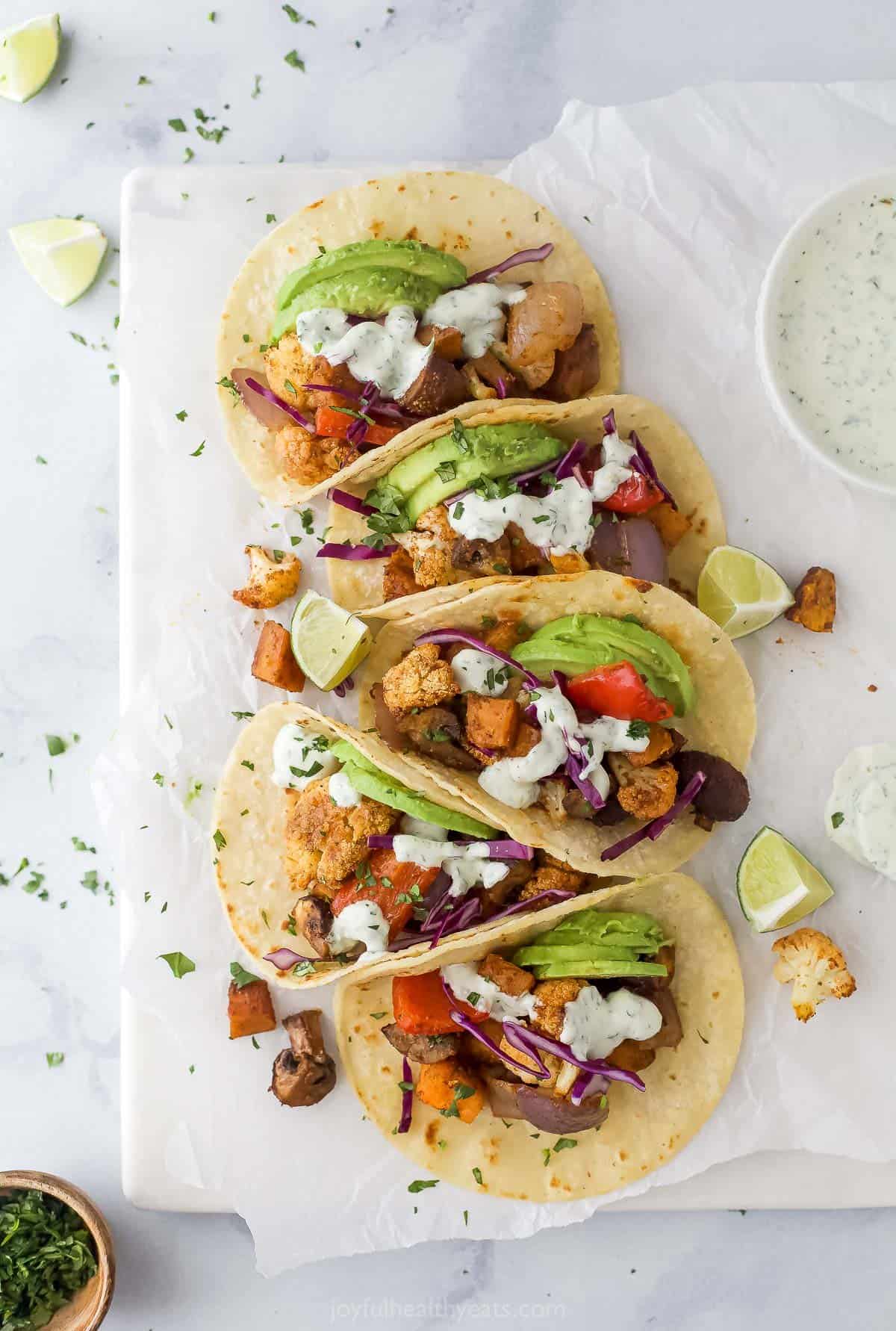This crispy baked bacon recipe is the perfect way to prepare lots of your favorite breakfast side at the same time. Five homemade vegetable tacos with homemade cilantro lime crema, avocado, and red cabbage.