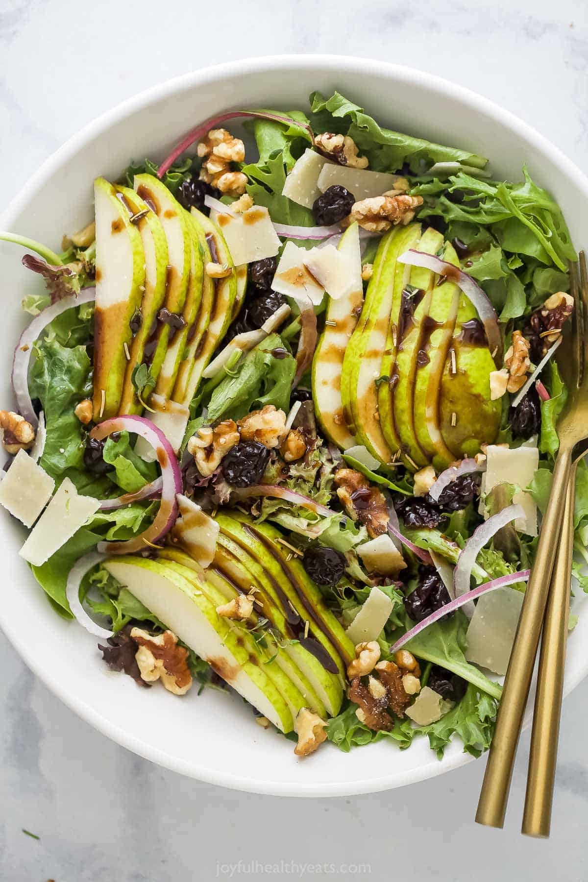 This 20-minute pear walnut salad recipe with tart cherries and homemade balsamic vinaigrette is an easy holiday side. Large bowl of pear walnut salad with dried cherries and parmesan cheese.