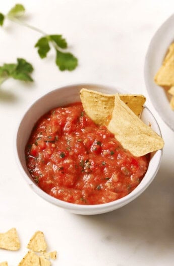 Roasted tomato salsa in a bowl with two tortilla chips.