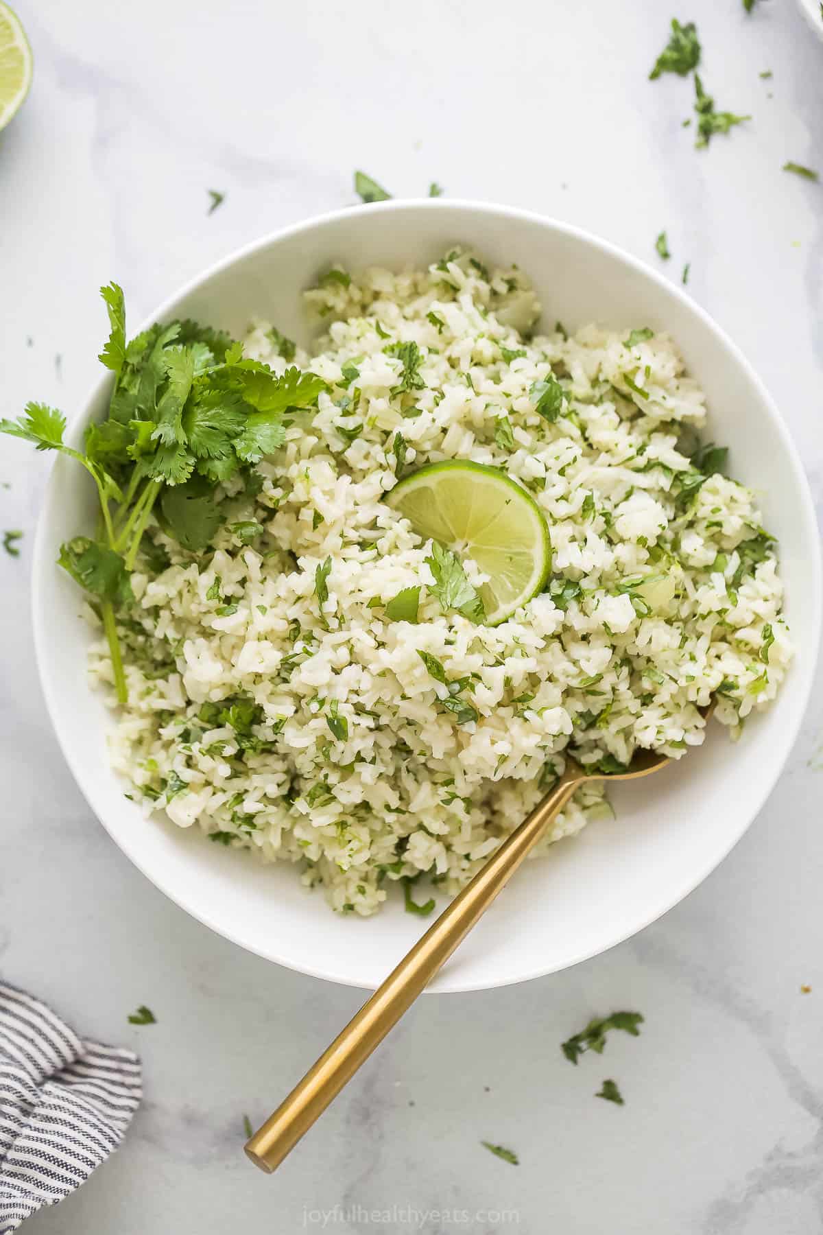 This zesty cilantro lime rice recipe with fragrant garlic and sautéed onions is an easy 20-minute side for weeknights. Bowl of homemade cilantro lime rice with a lime wedge.