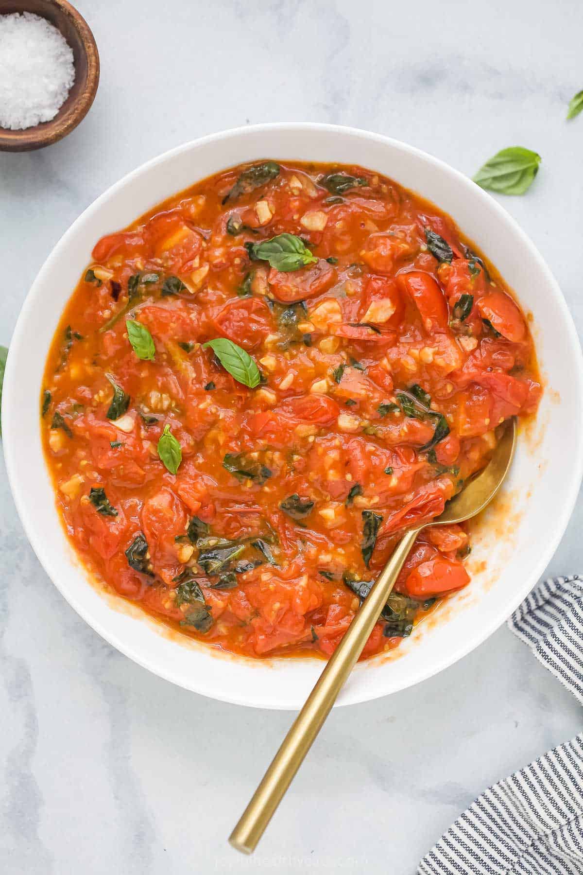 You’ll never buy a jar at the store again when you’ve got this trusty pasta sauce recipe! Tomato, basil and lots of garlic make it delicious. Overhead view of homemade pasta sauce in bowl with spoon