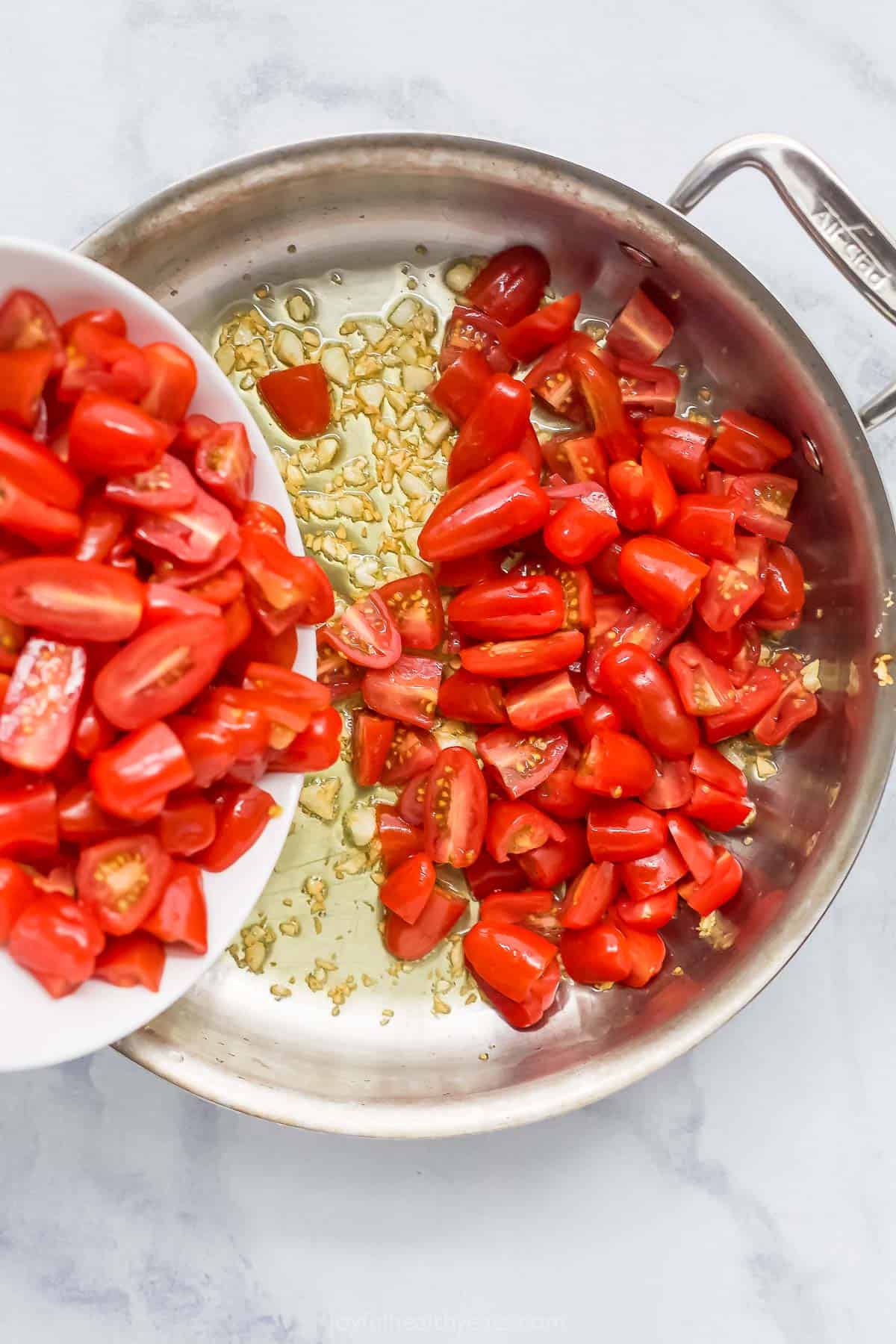 Pouring tomatoes into skillet with oil and garlic