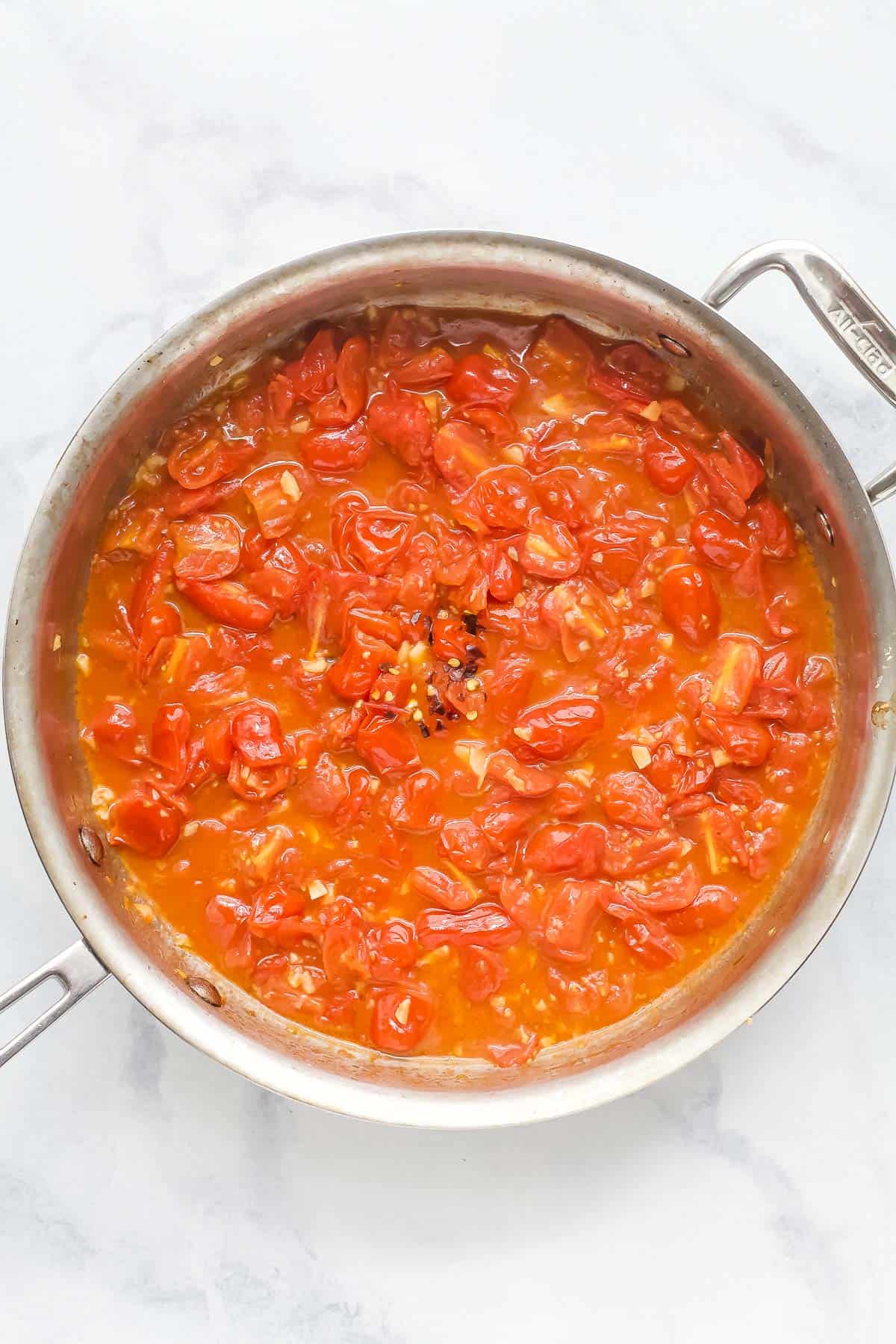 Overhead view of tomatoes simmering in skillet