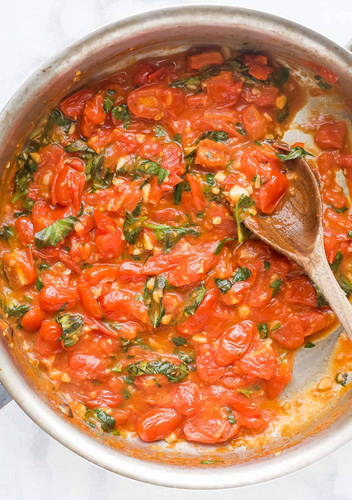 Overhead view of homemade pasta sauce in skillet with wooden spoon
