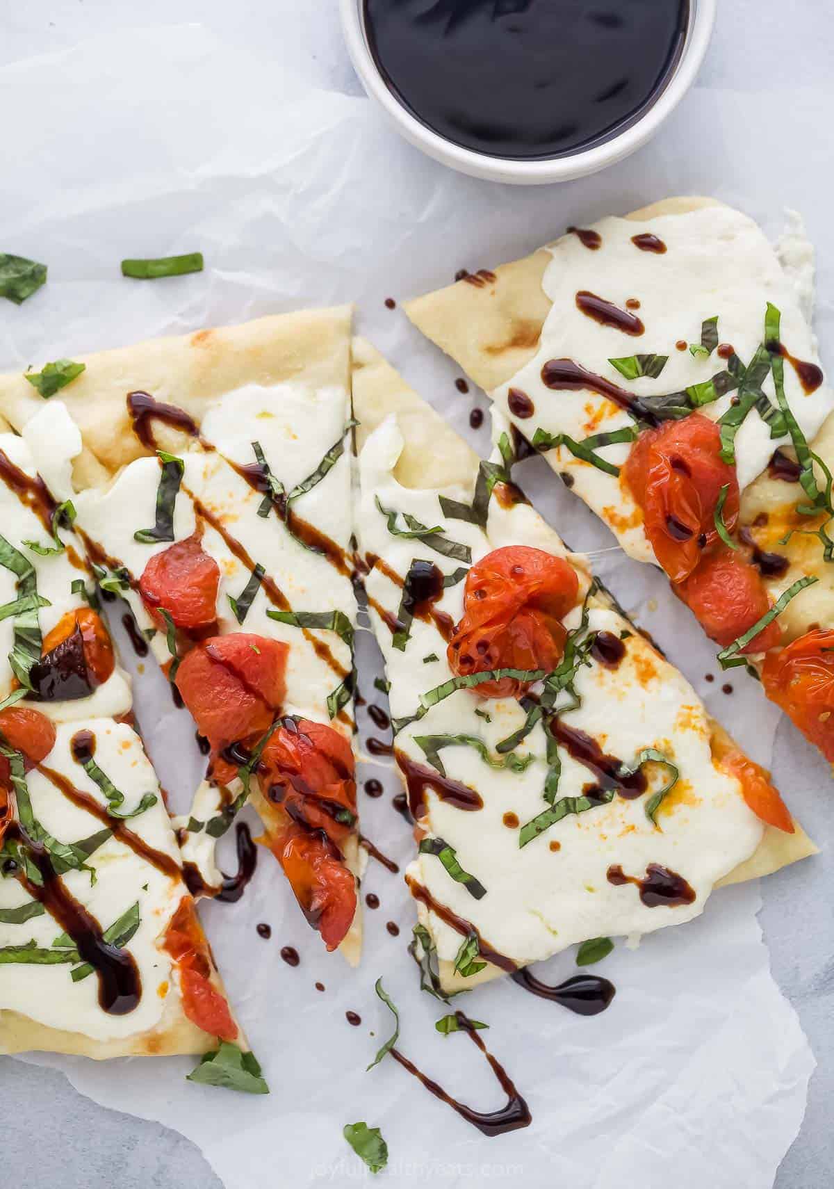 This Italian-style caprese flatbread recipe with melty mozzarella, roasted tomatoes, basil, and balsamic reduction is an easy pizza dinner. Caprese flatbread with mozzarella, roasted tomatoes, fresh basil, and balsamic reduction.
