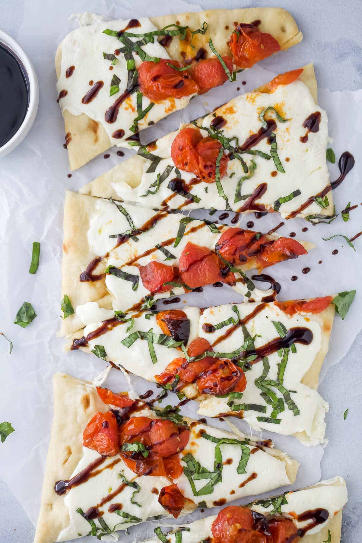 Sliced flatbread pizzas with tangy balsamic reduction drizzle on top. 