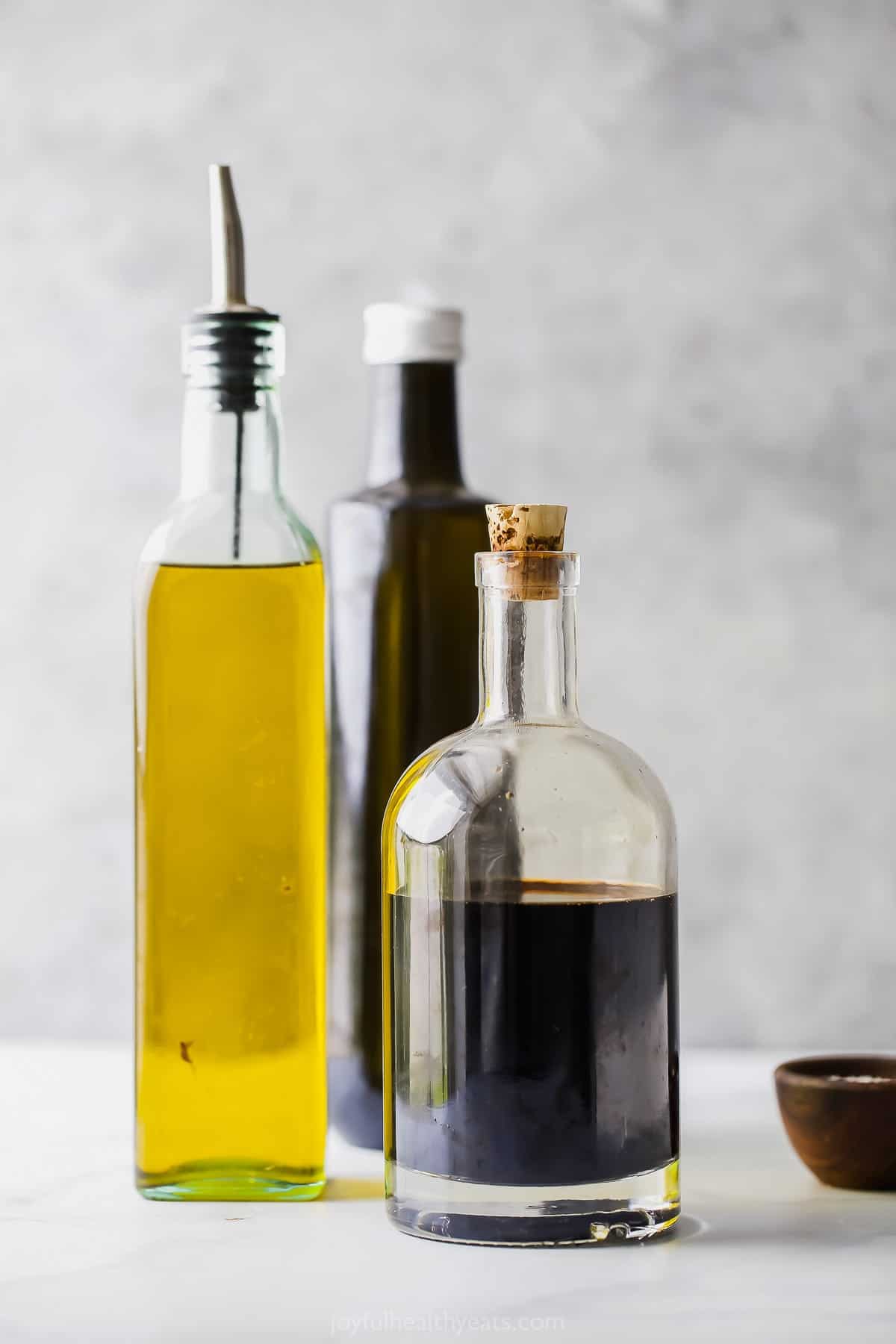 This balsamic reduction recipe is made with just one ingredient - balsamic vinegar! It's perfect for salads, chicken, peaches, and more. Bottles of balsamic vinegar and olive oil.