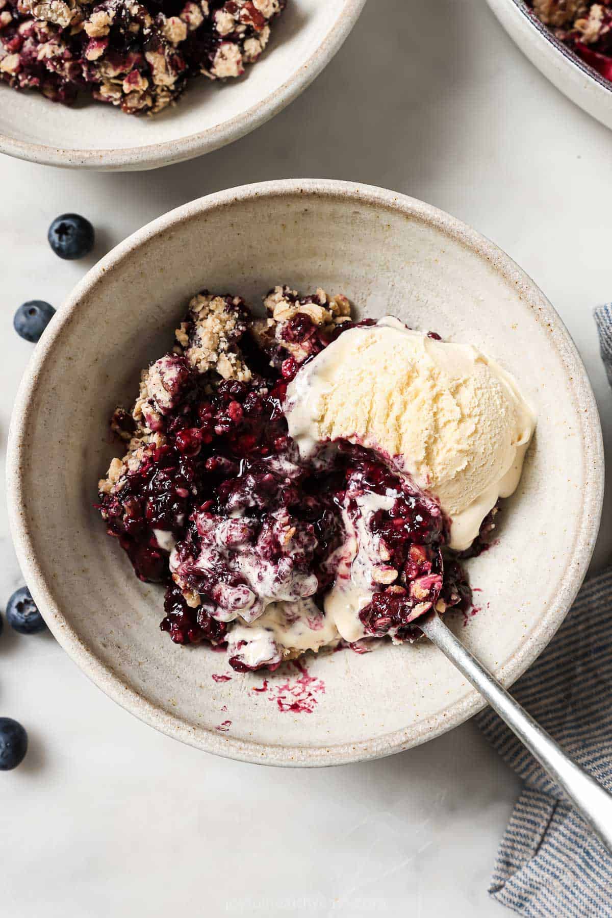 Bowl of blueberry cobbler with vanilla ice cream. 