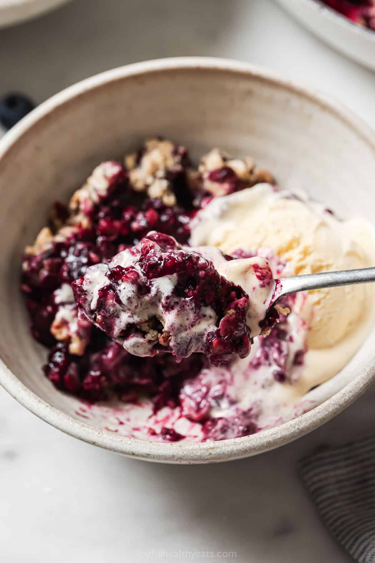 Spoonful of blueberry oat cobbler with ice cream. 