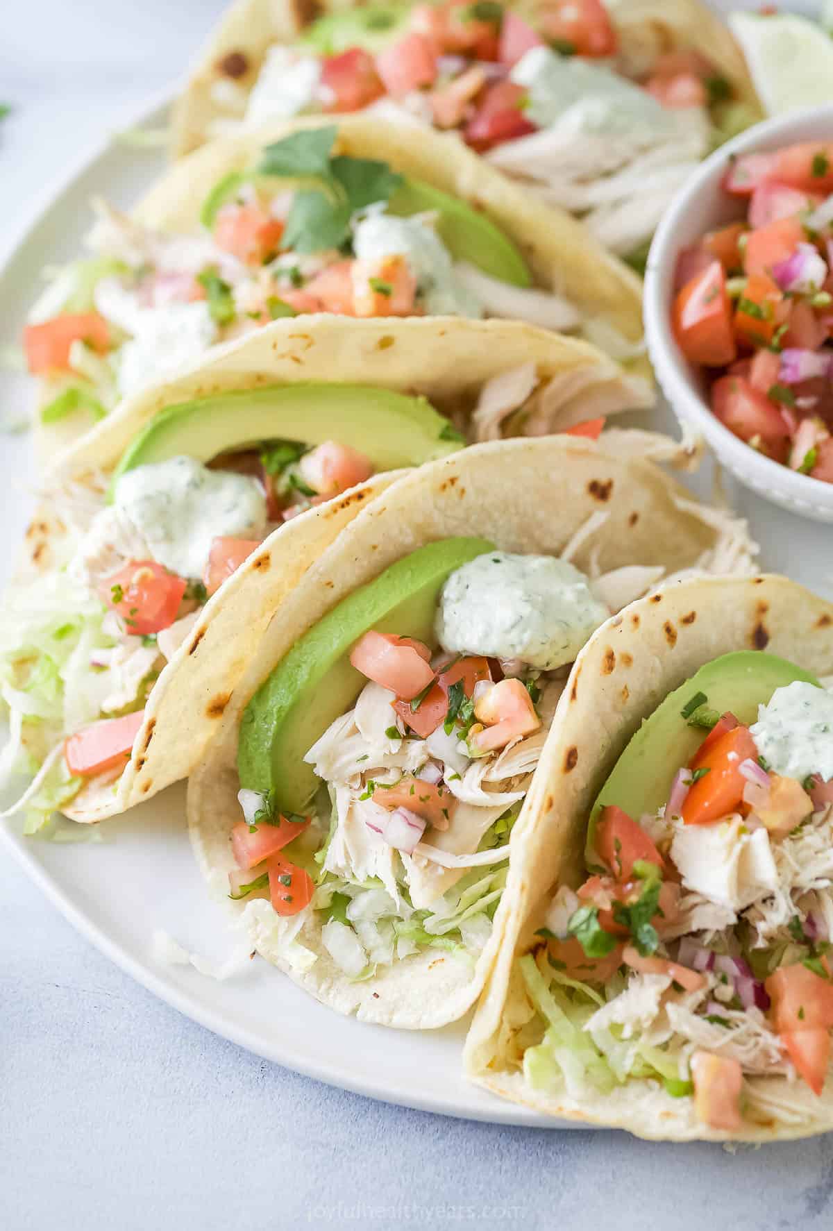 This rotisserie chicken tacos recipe with onions, sweet peppers, creamy avocado, and queso fresco are an easy way to use up leftovers. Rotisserie chicken tacos in warm corn tortillas, with avocado, cilantro-lime crema, and other toppings.