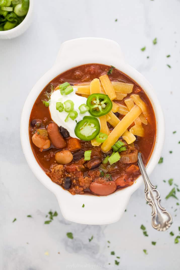This crock pot beef and three bean chili is a hearty make-ahead chili recipe that's loaded with vegetables, browned beef, and so much flavor! Close up of a bowl filled with three bean chili.