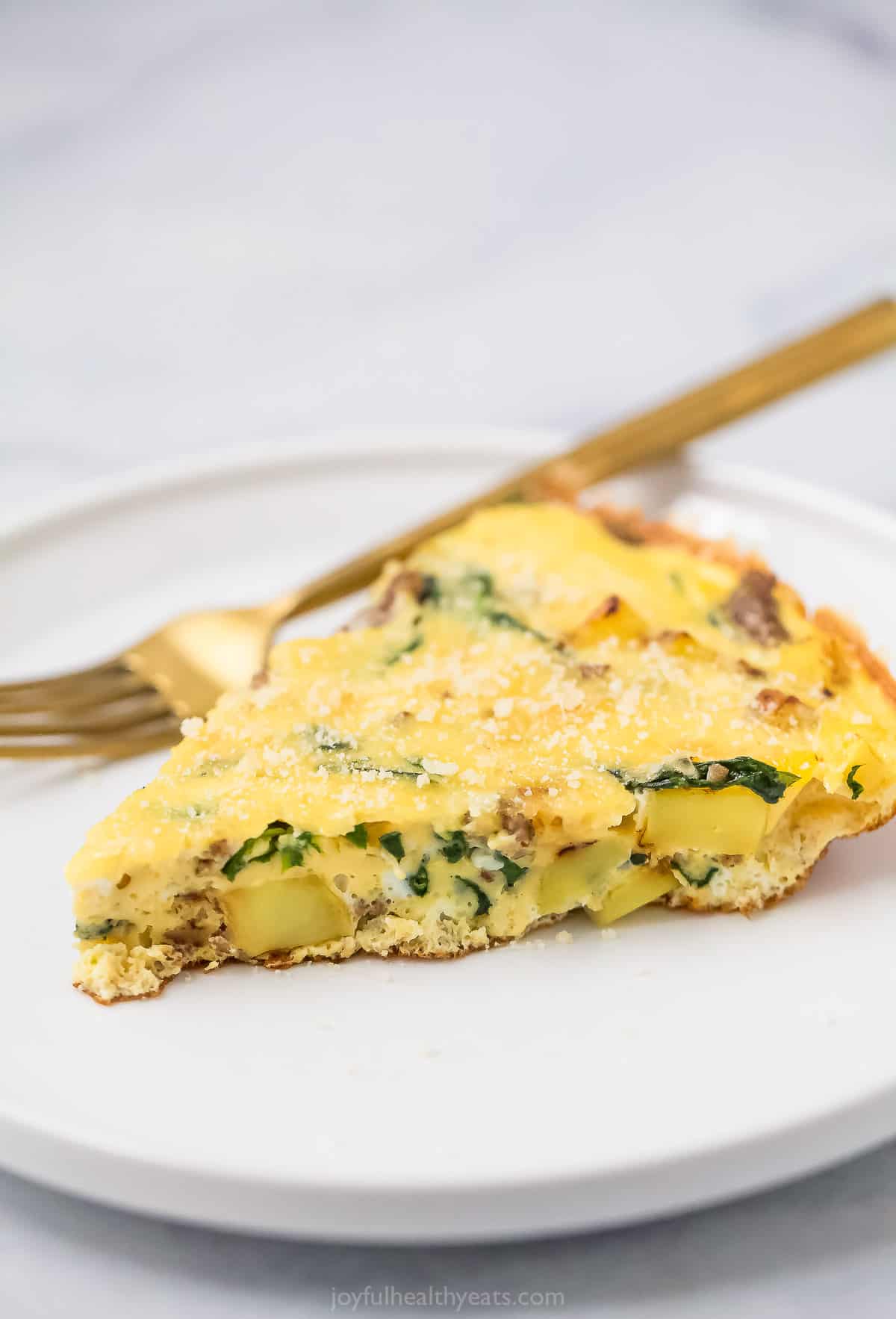 This easy potato frittata recipe with savory pork sausage and spinach is perfect for brunch. You'll love that it's ready in 25 minutes. Potato frittata slice on a plate.