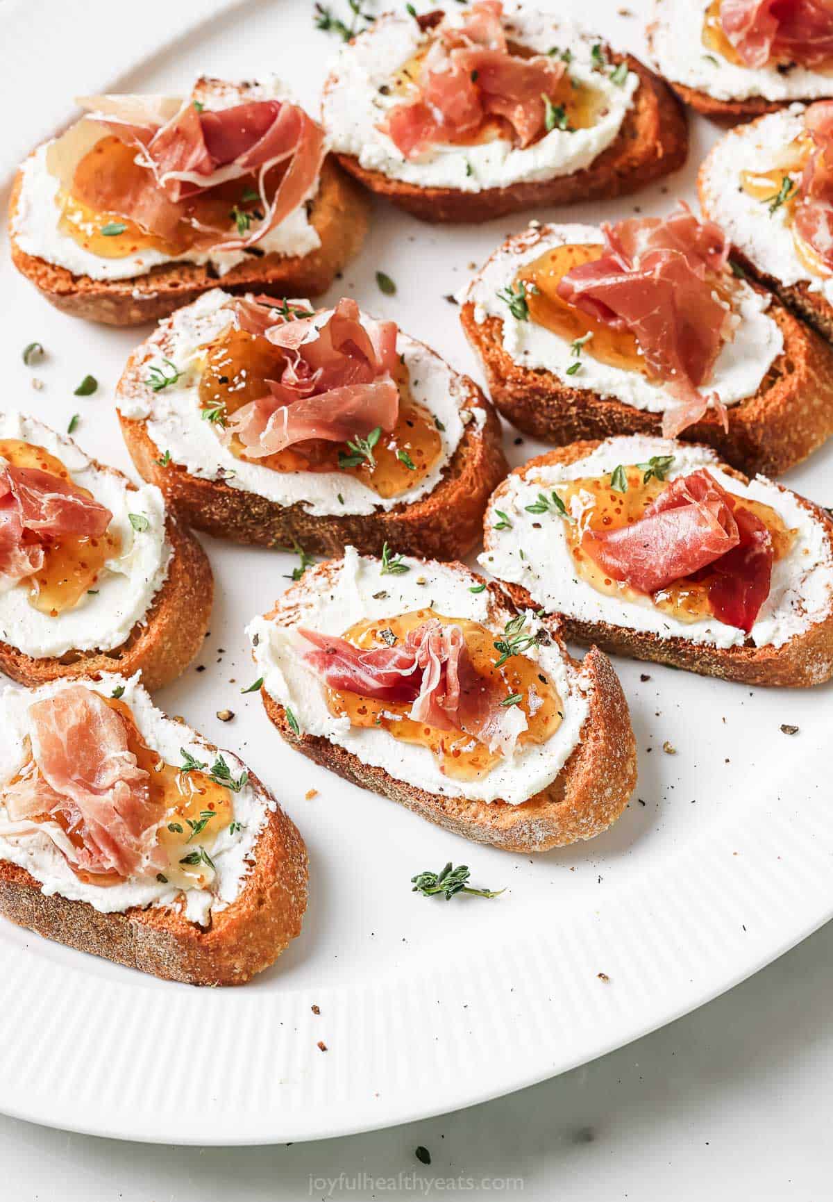 Close-up of homemade crostinis with goat cheese, fig jam, and prosciutto. 