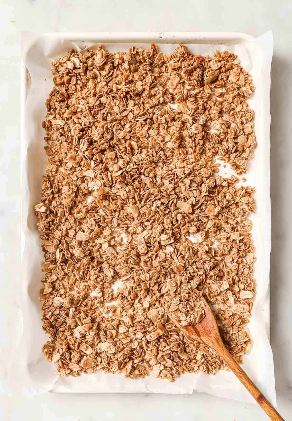 Overhead view of granola on pan with wooden spoon