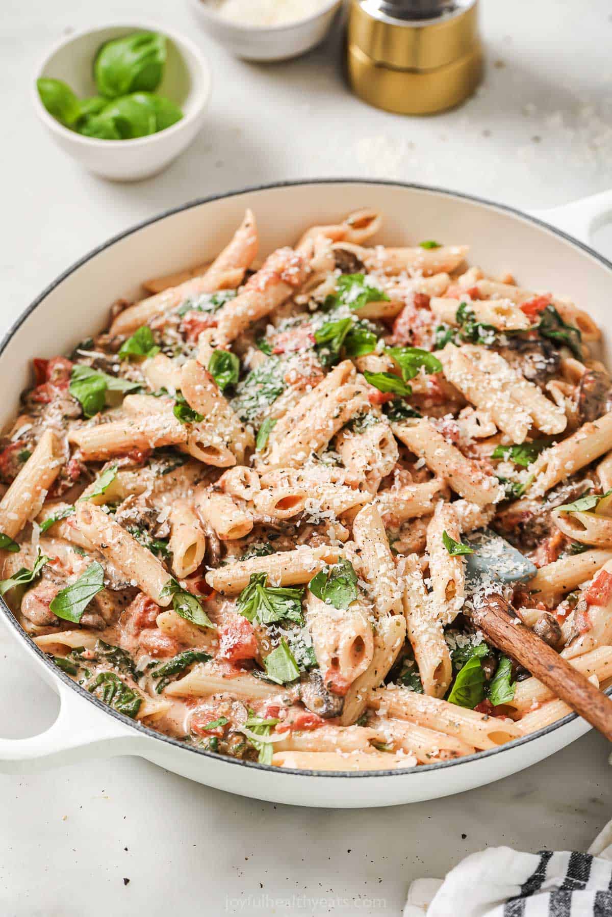 This tomatoey spinach mushroom pasta recipe with Italian herbs and creamy sauce is an easy 25-minute dinner. Creamy spinach mushroom pasta in the skillet.