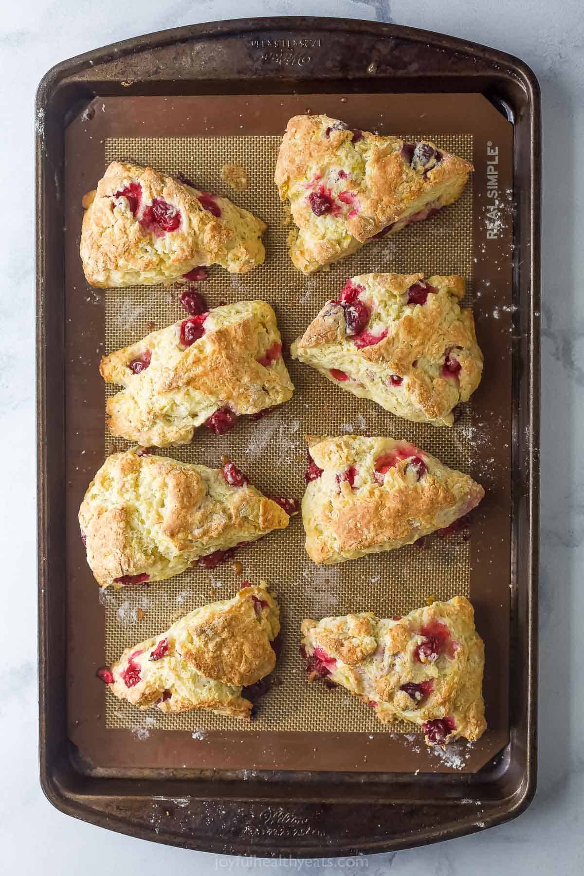 This 25-minute cranberry orange scones recipe is packed with tart and zesty goodness that's way better than your local coffee shop. Freshly baked cranberry orange scones in the baking sheet.