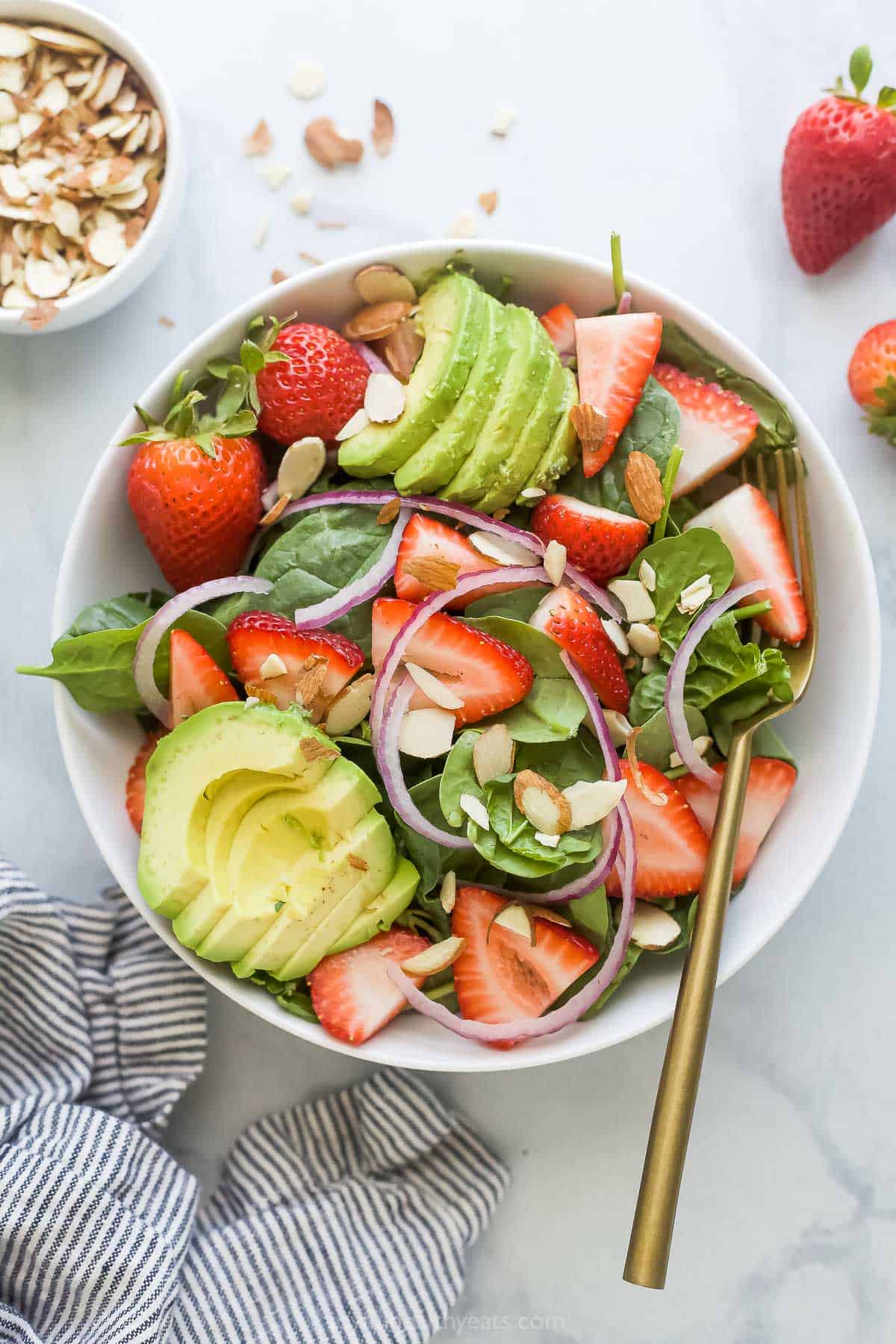 This easy strawberry avocado salad with spinach and honey mustard dressing is a refreshing summer recipe you'll love. Despite being ready in 2 steps, it's full of nutty, fruity, and crunchy goodness. Bowl of strawberry avocado salad.