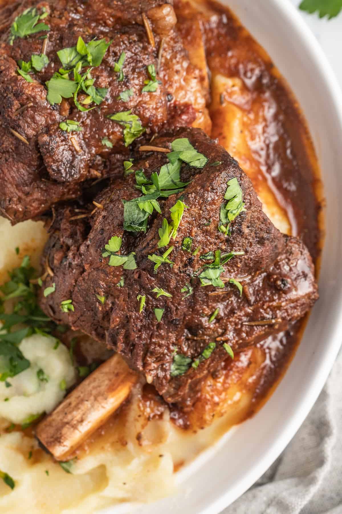 Slow Cooker Balsamic Braised Beef Short Ribs are a hearty Paleo recipe. Made with juicy beef short ribs & balsamic vinegar, simple yet fancy! brasied balsamic short ribs plated with pureed potatoes and garnished with herbs