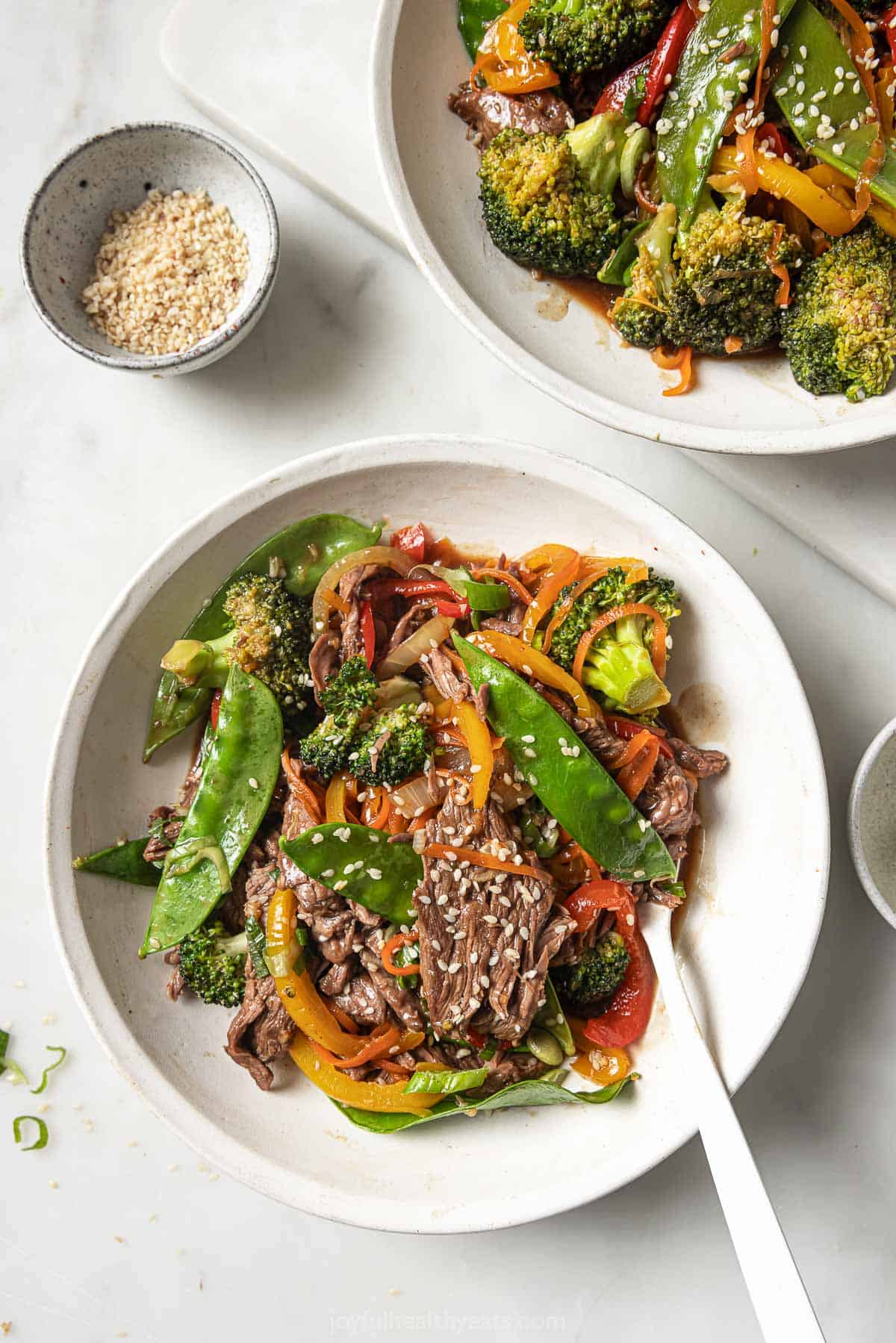 This hearty, Asian-style steak stir fry recipe with crisp veggies and sweet-and-spicy sauce is an easy weeknight dinner. Bowl of steak stir fry recipe with veggies in homemade sweet-and-spicy sauce.