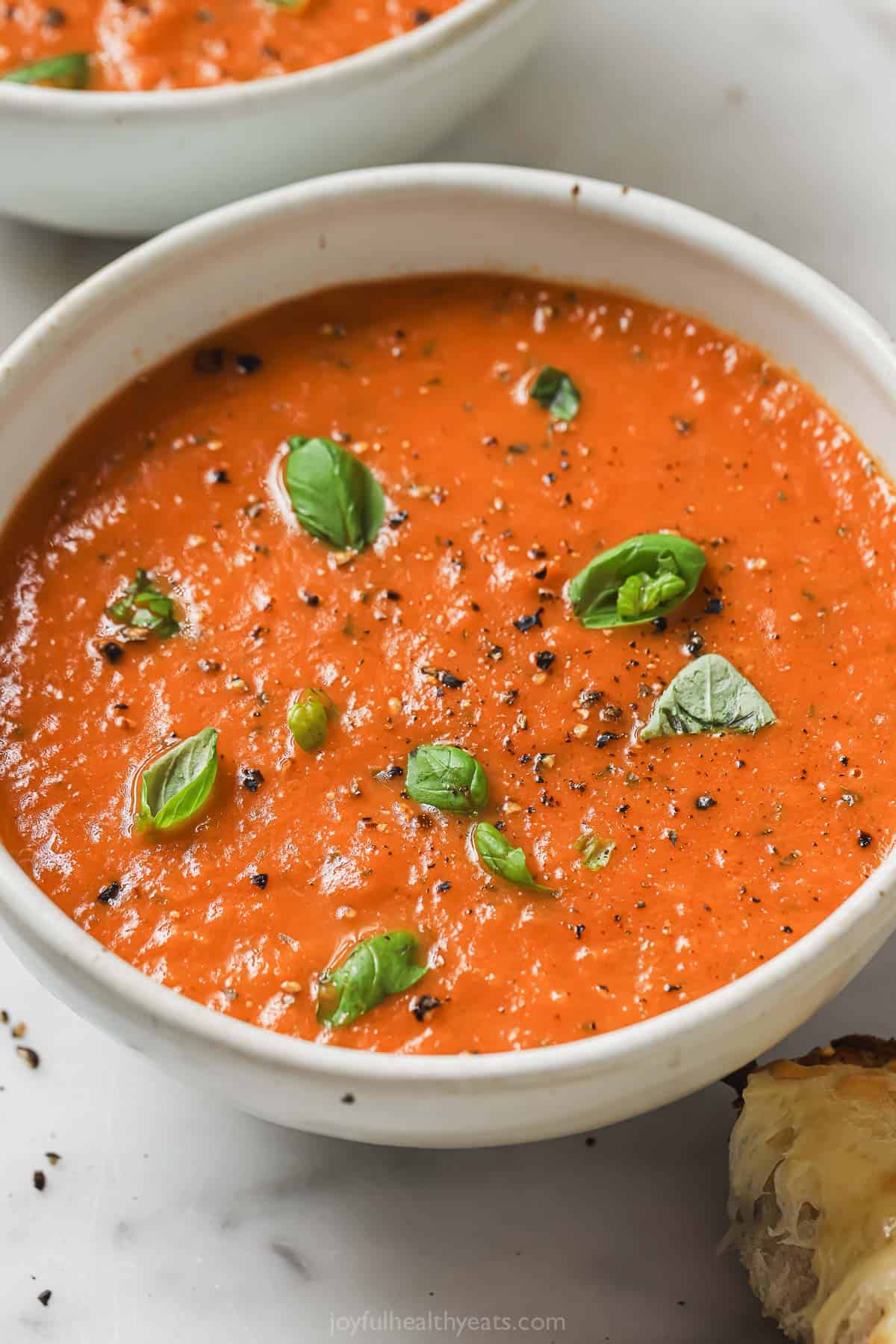 This thick and creamy tomato basil soup with hints of garlic is the perfect weeknight dinner and great for dipping with grilled cheese. Bowl of tomato basil soup.