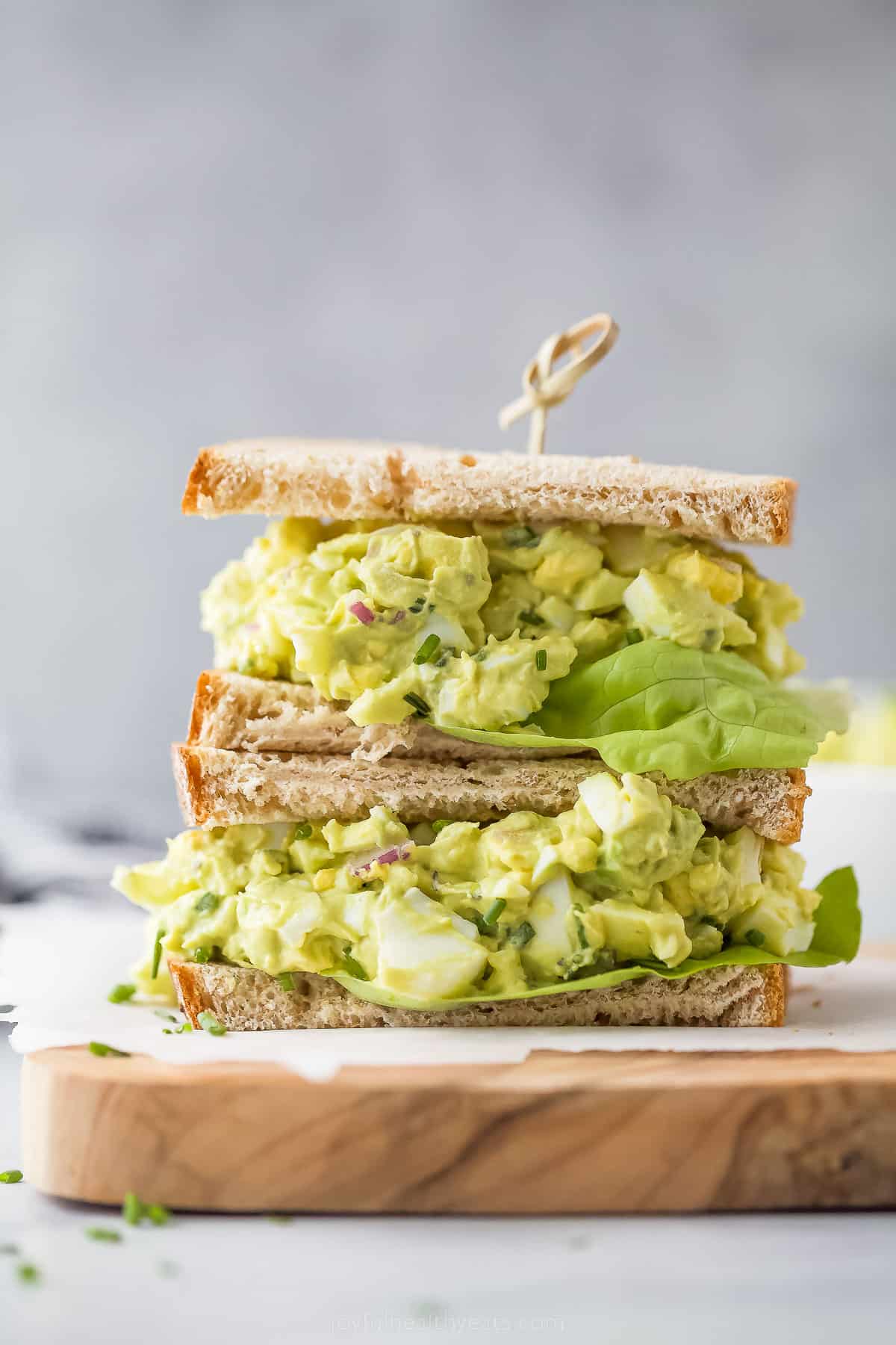 This Avocado Egg Salad is a healthy & satisfying salad made with less mayo! It's perfect for breakfast or lunch. a stacked sandwich with bread, avocado egg salad and lettuce
