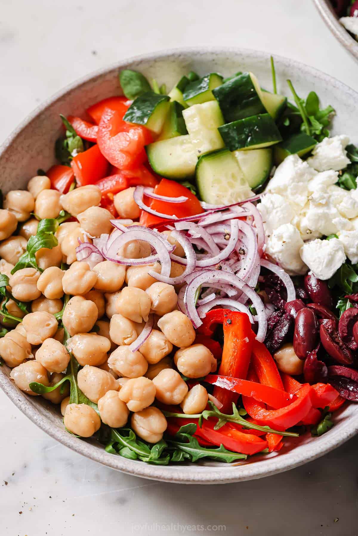 This 10-minute Mediterranean salad recipe with cucumber, chickpeas, feta, and Greek vinaigrette is a refreshing summer side. Bowl of Mediterranean salad with homemade Greek vinaigrette.