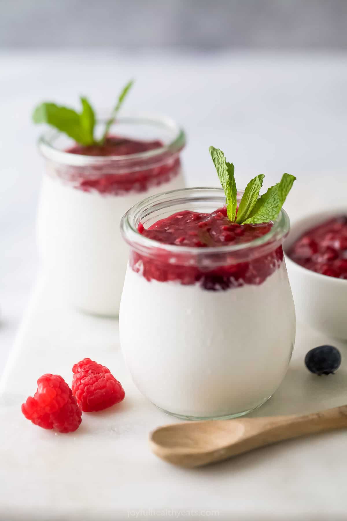 This velvety coconut panna cotta recipe with sweet berry compote is an impressive no-bake Italian dessert you'll love. Silky coconut panna cotta with berry compote in crystal serving glasses.