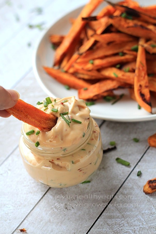 These easy baked sweet potato fries are cooked until they're perfectly crispy, then served alongside a smoky chipotle lime sauce for dipping! A crispy oven-baked sweet potato fry being dipped into a jar of homemade aioli.