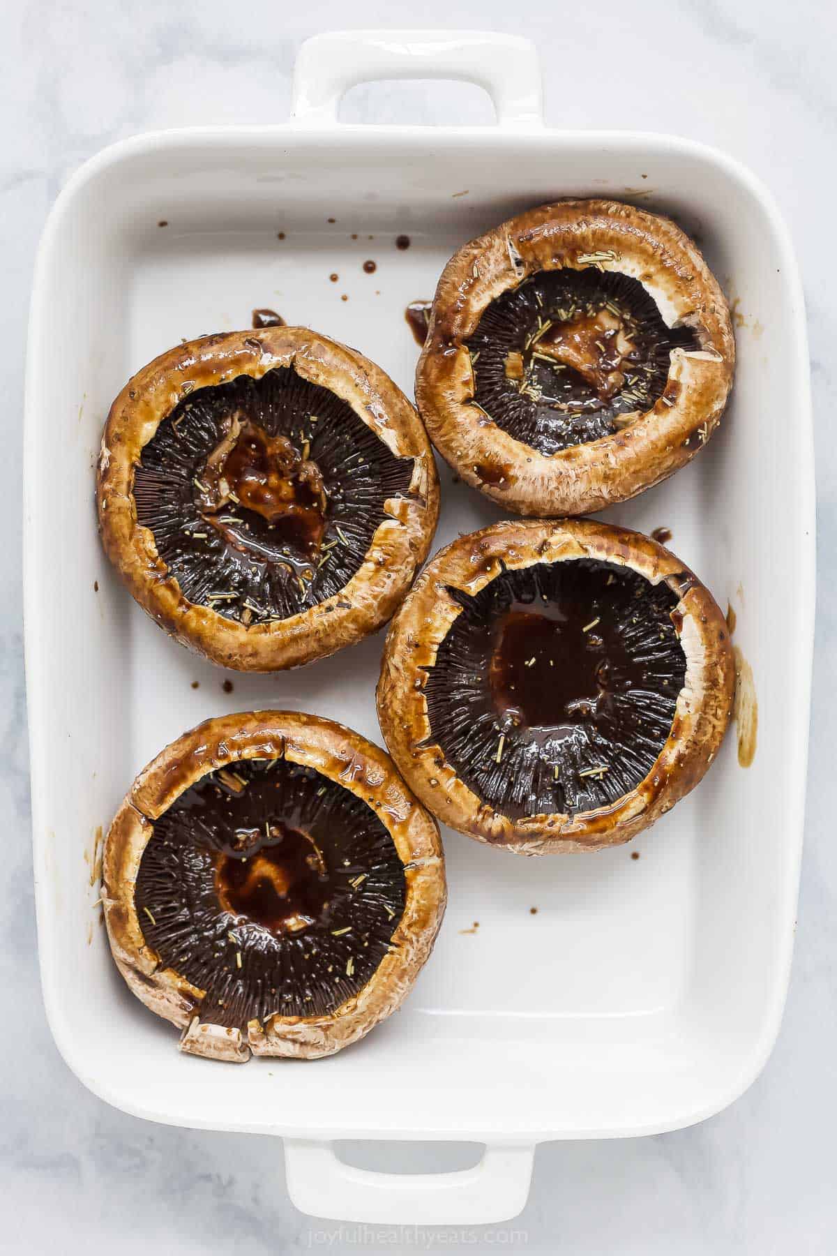 Overhead view of marinated portobello mushrooms in baking dish