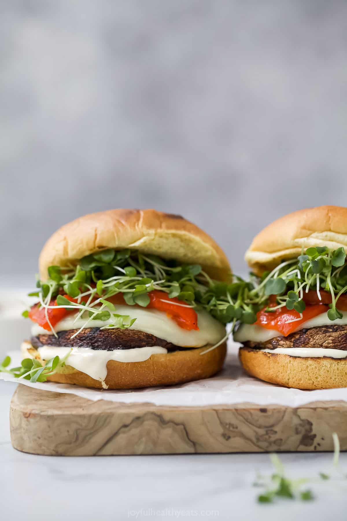Two portobello mushroom sandwiches with cheese, roasted red pepper, and microgreens