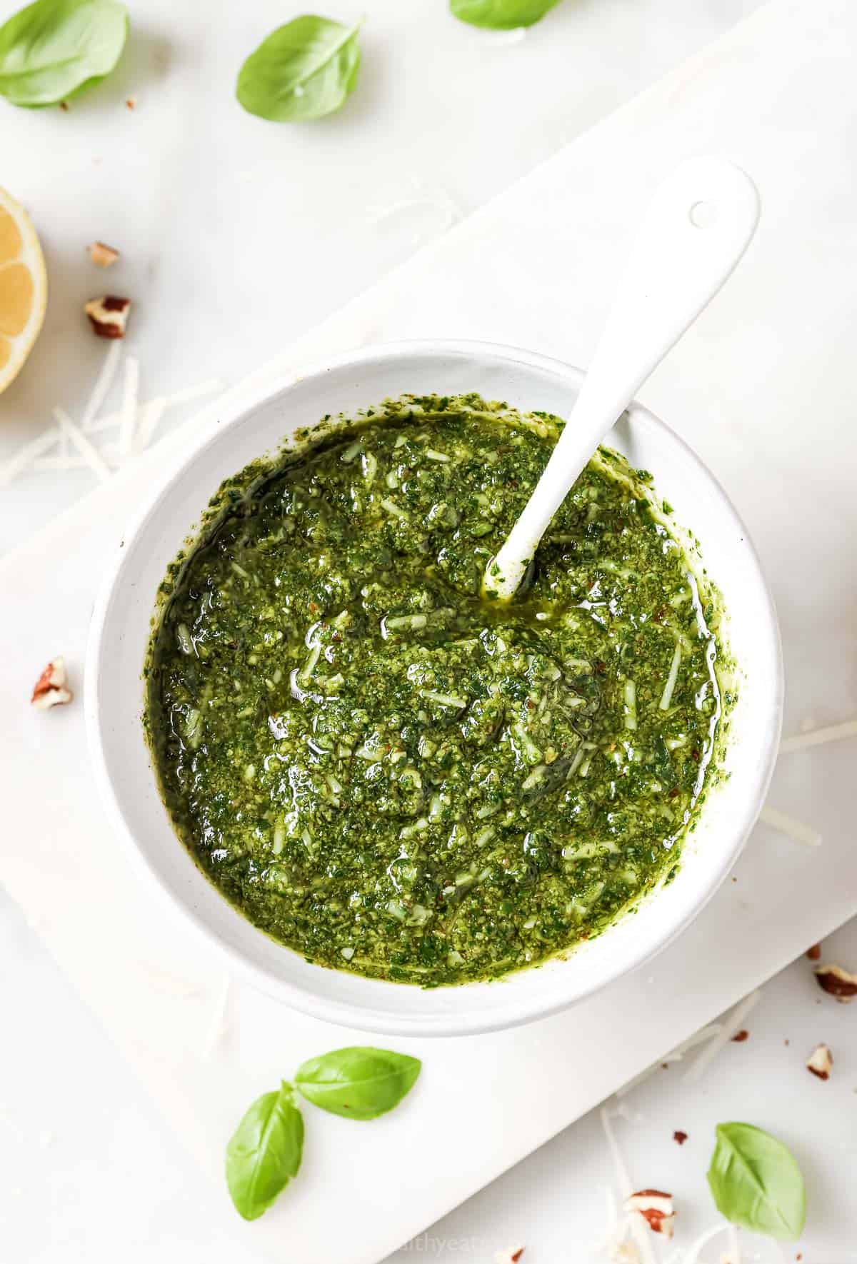 Overhead view of homemade basil pesto in bowl with spoon