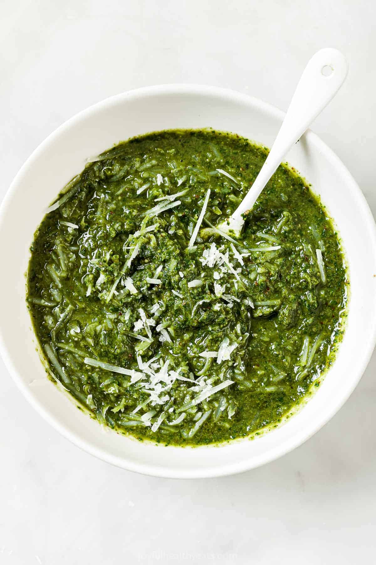 Stirring Parmesan into bowl of homemade basil pesto