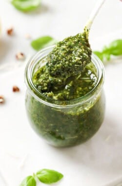 Spoonful of homemade basil pesto held over jar