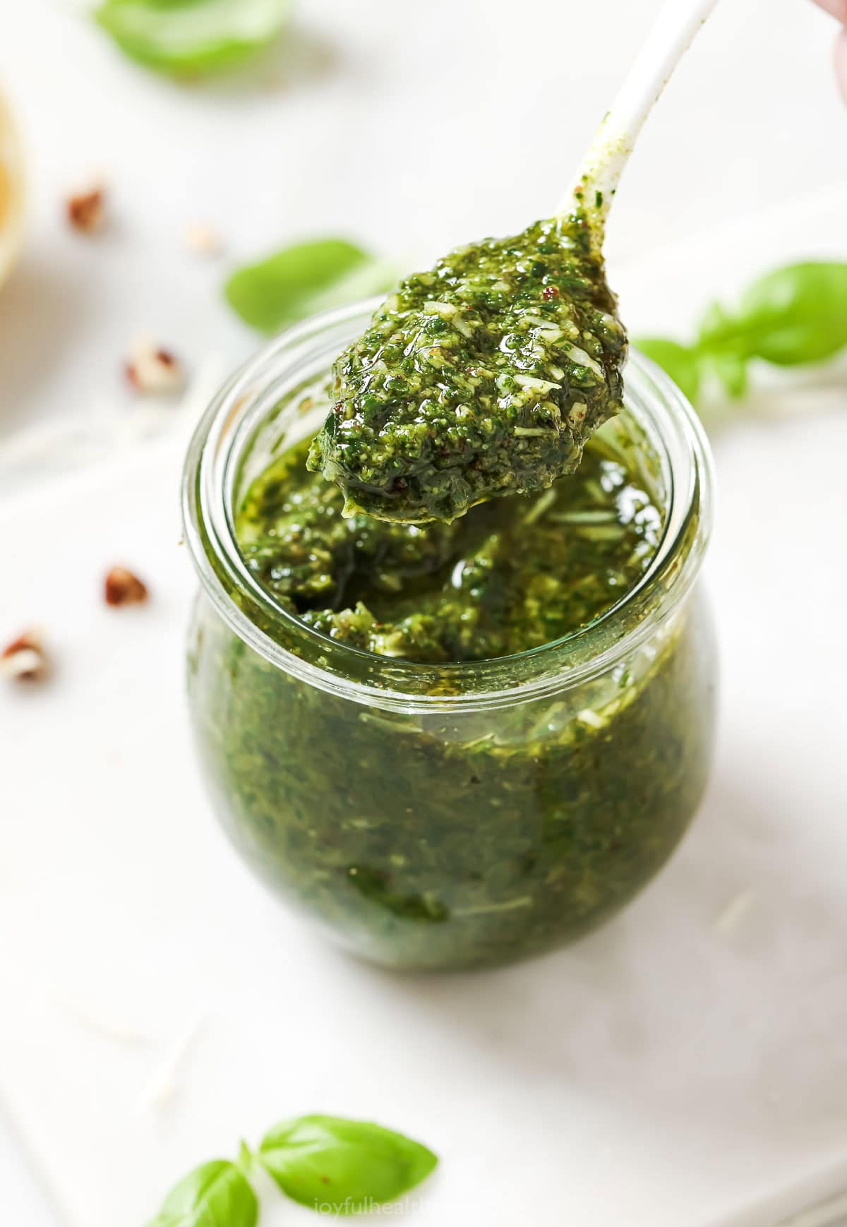 Spoonful of homemade basil pesto held over jar