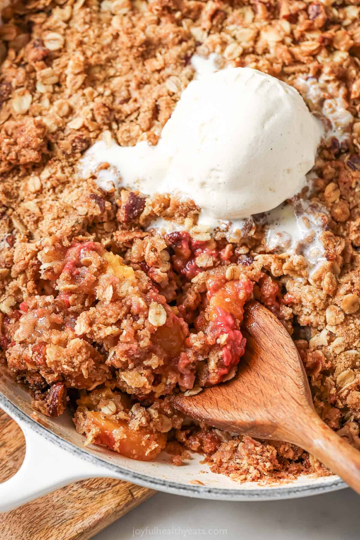 Skillet of raspberry peach crisp with scoop of ice cream on top