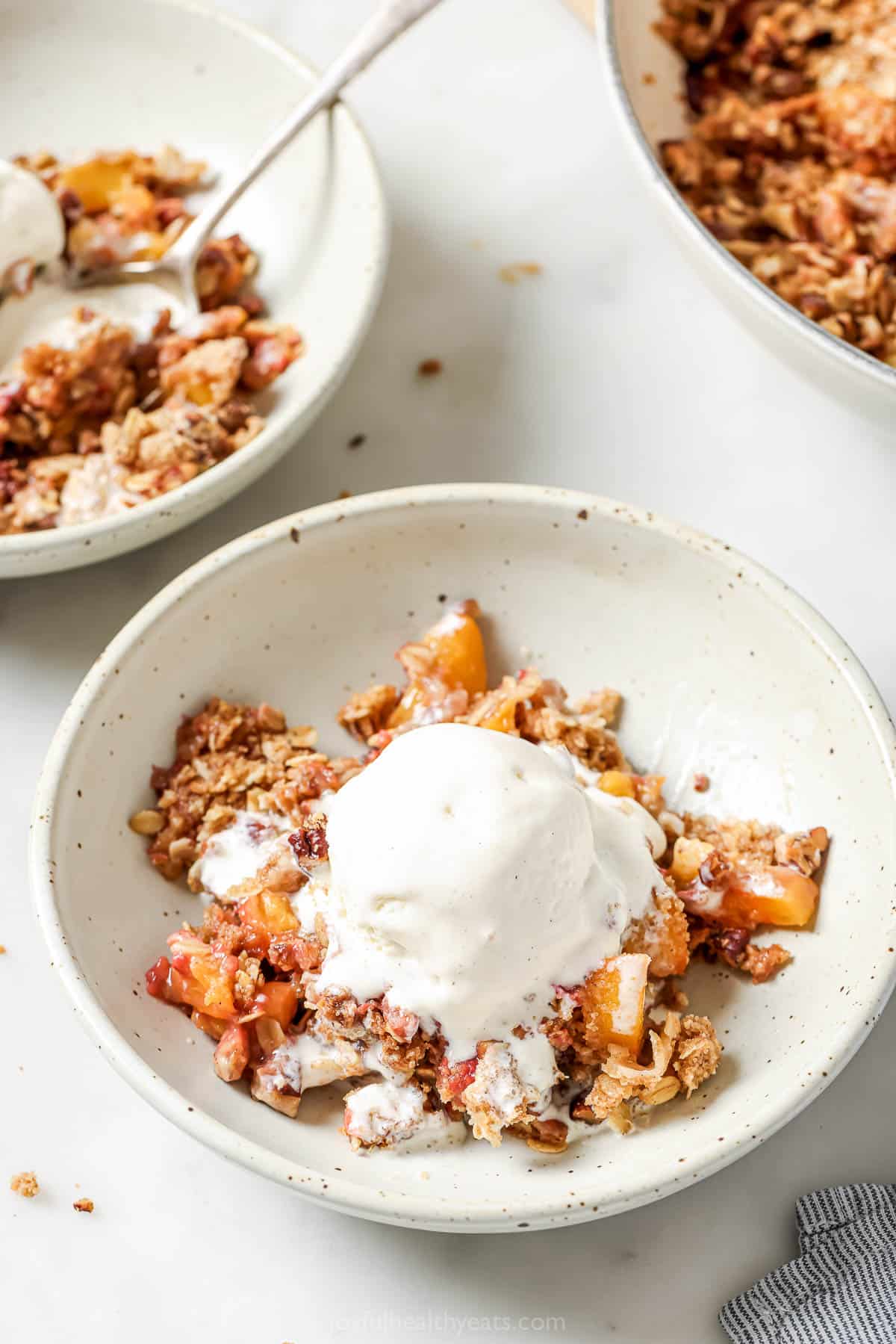 Bowls of raspberry peach crisp with vanilla ice cream