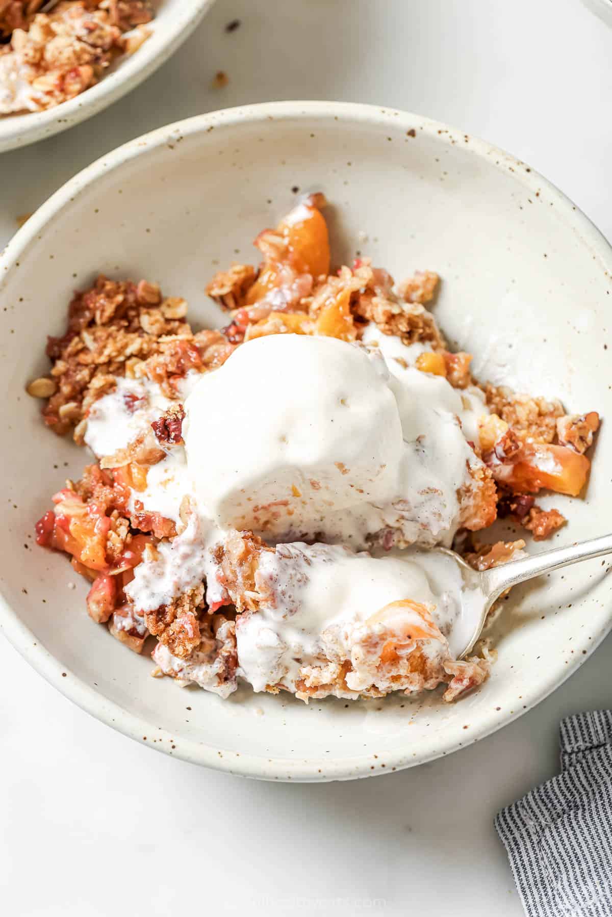 crunchy oatmeal pecan crumble. An easy summer dessert! Bowl of raspberry peach crisp with scoop of vanilla ice cream