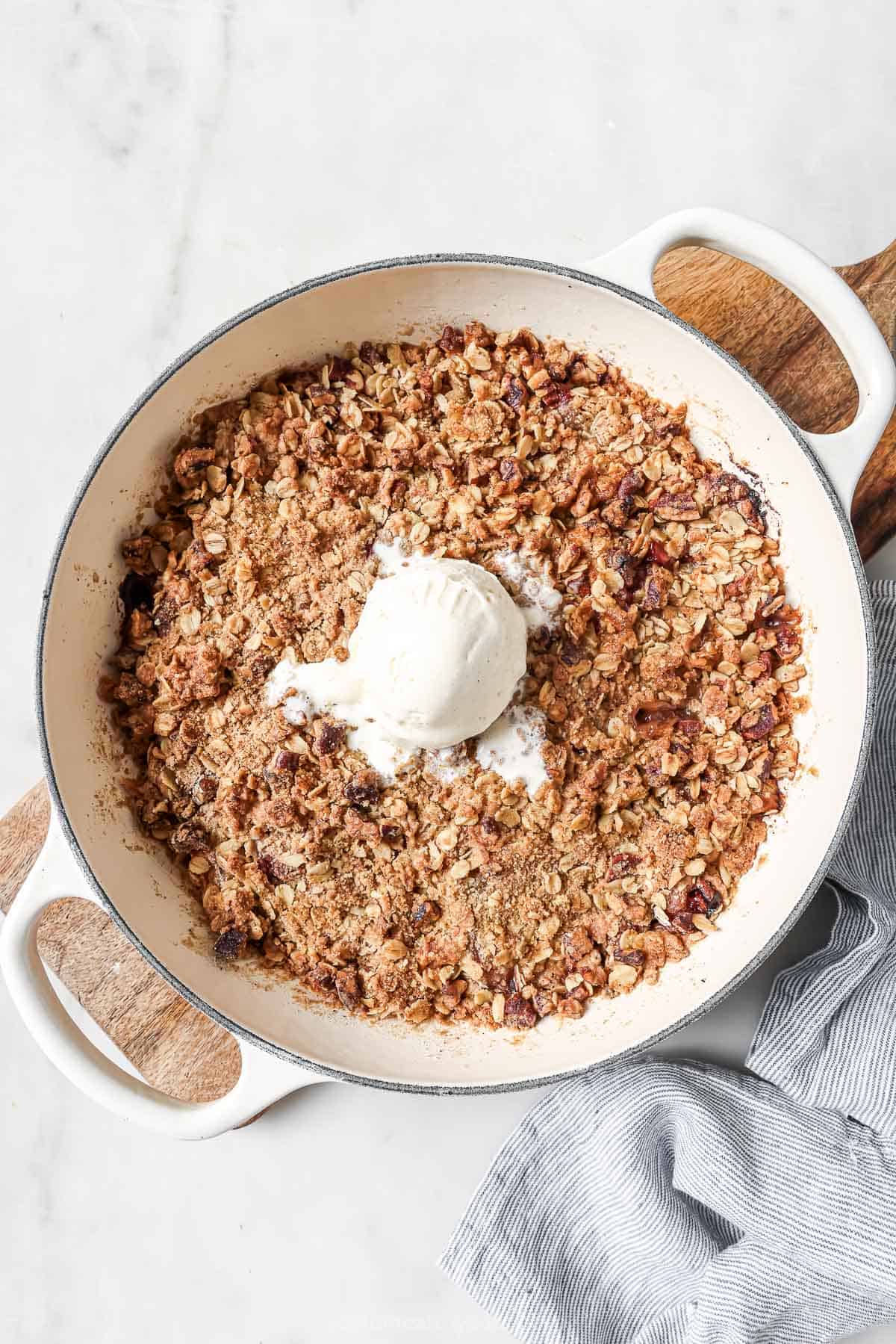 Skillet of raspberry peach crisp with scoop of vanilla ice cream