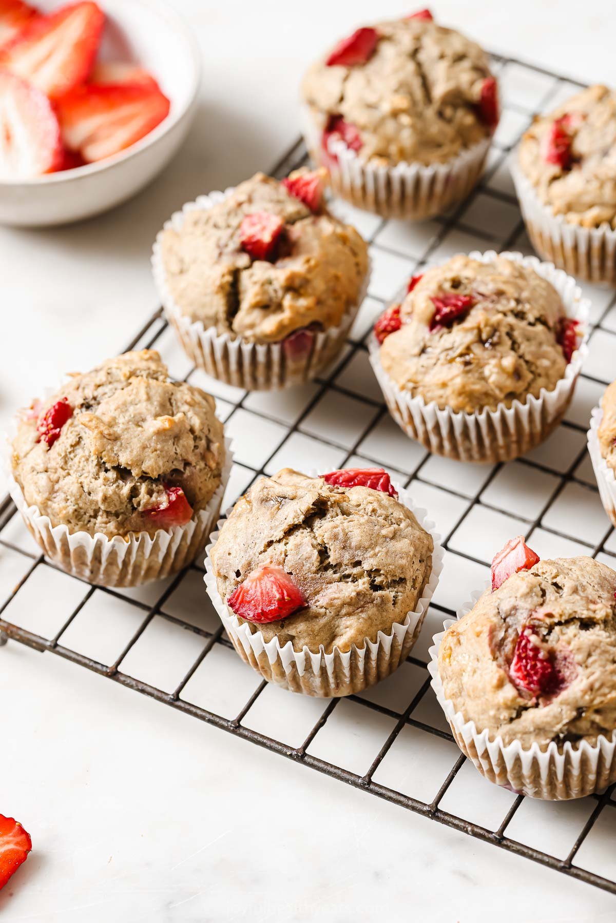 This fluffy strawberry banana muffins recipe is naturally sweetened with maple syrup for the perfect morning bite. Fluffy strawberry banana muffins on a wire rack.