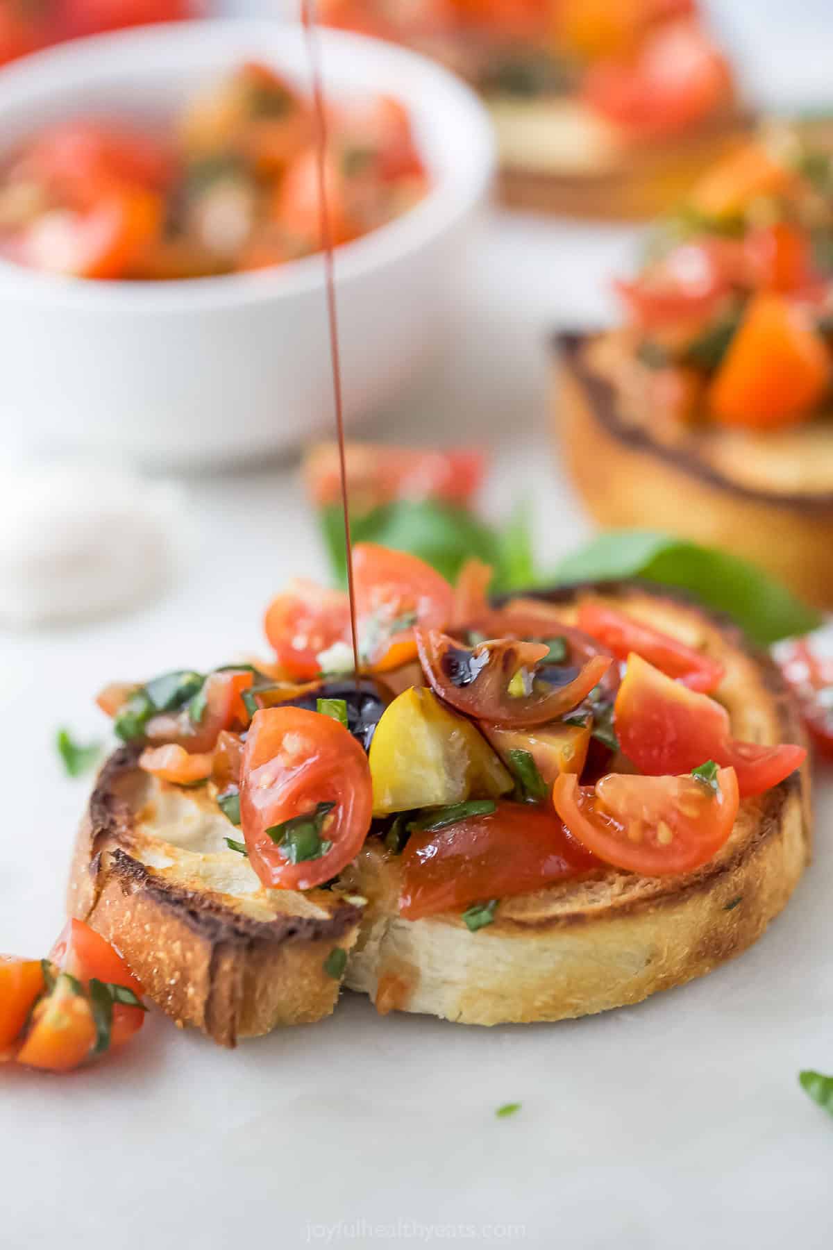 Drizzling balsamic vinegar onto tomato bruschetta