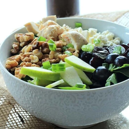 A Bowl of Chicken Feta Walnut Grape Salad Beside a Bottle of Honey Balsamic Vinaigrette