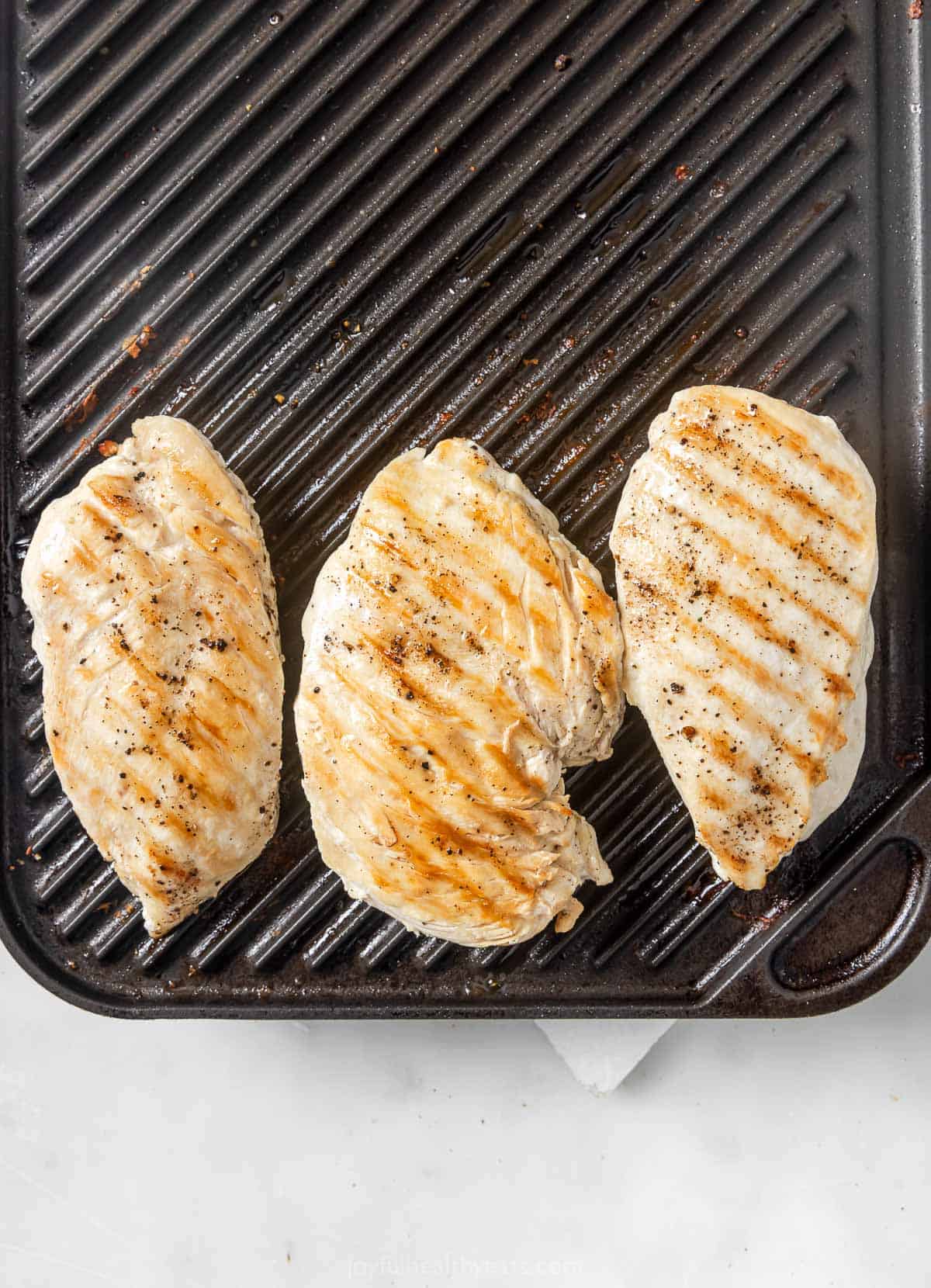 Overhead view of chicken cooking on indoor grill