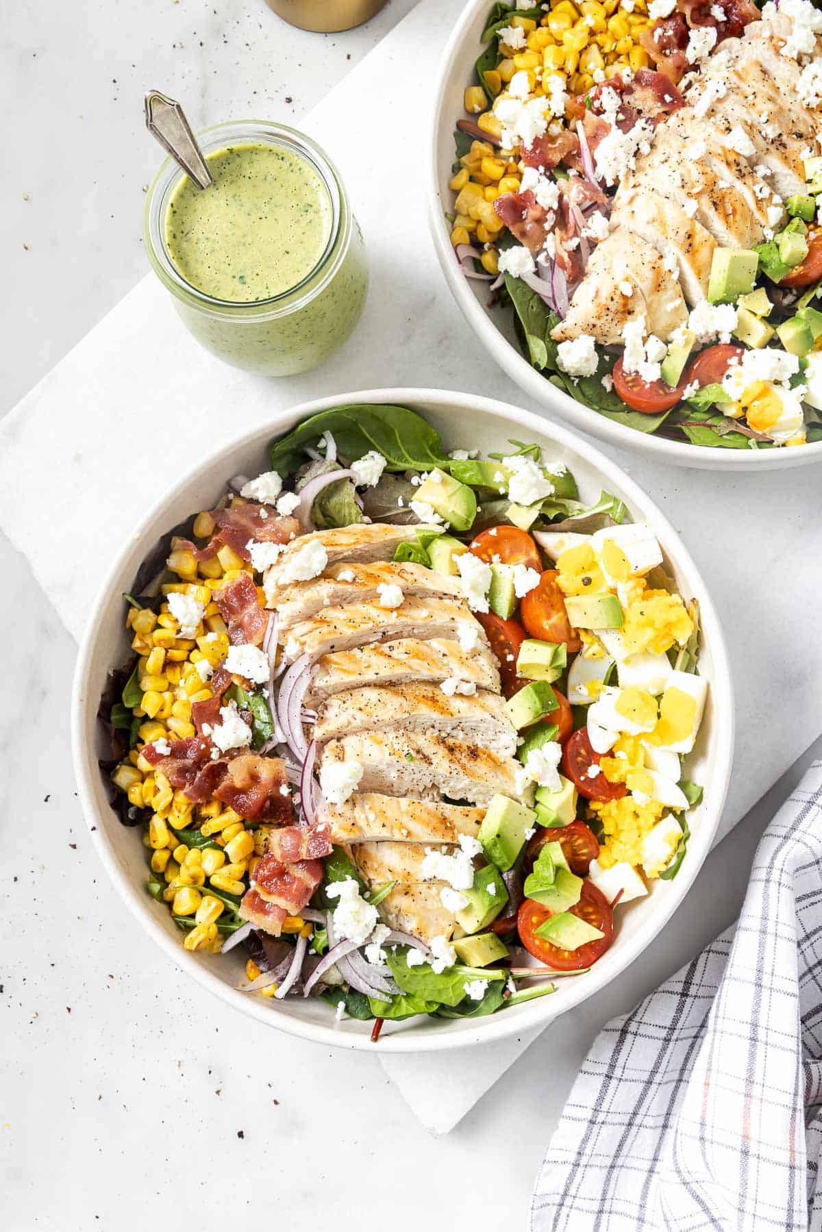 Chicken Cobb salad in two bowls with creamy poblano dressing in jar