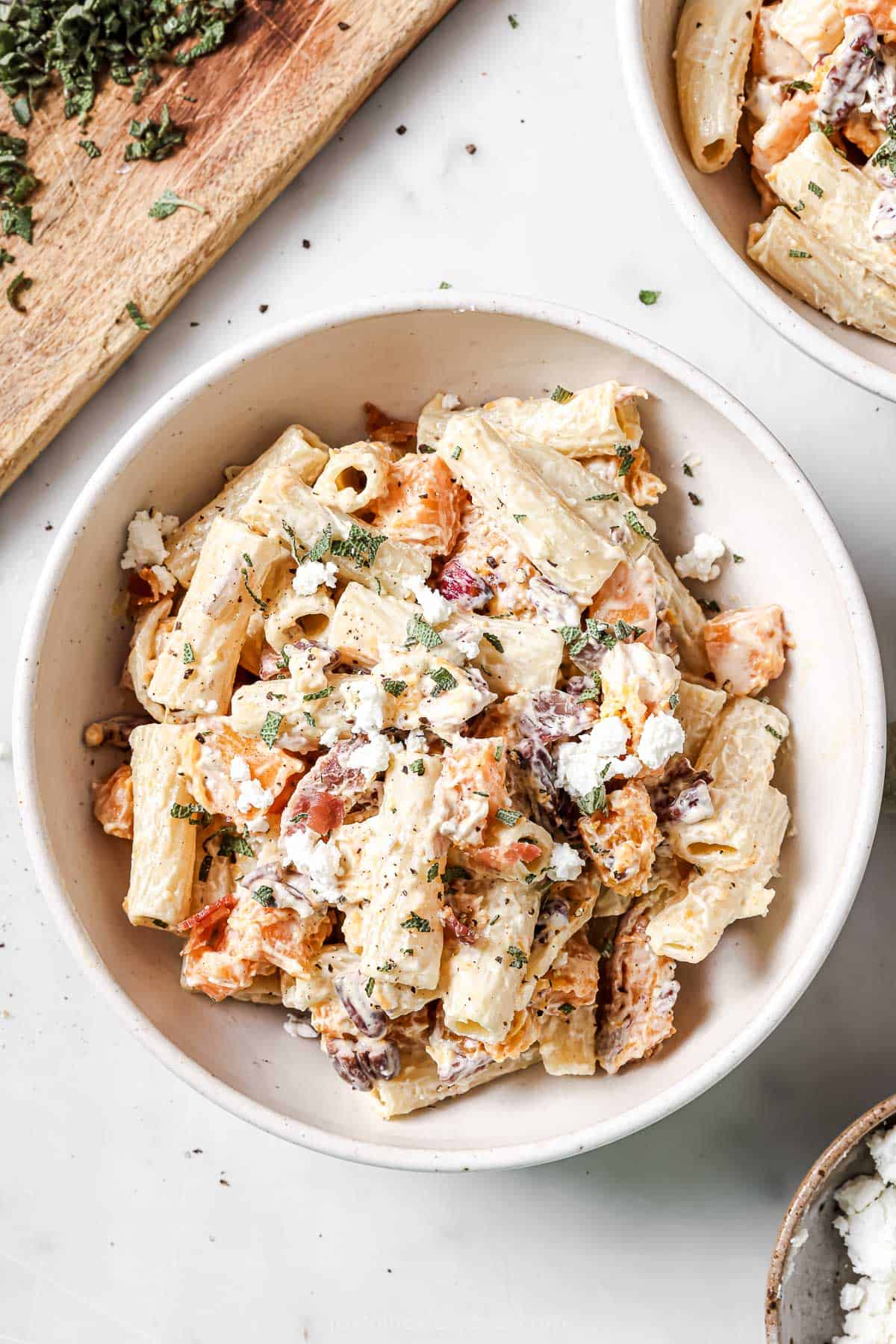 This tossed creamy goat cheese pasta recipe with crunchy pecans, smokey bacon, sweet butternut squash, and onions is perfect for weeknights. Creamy goat cheese pasta in a bowl with sweet butternut squash, smokey bacon, red onions, and crunchy pecans.