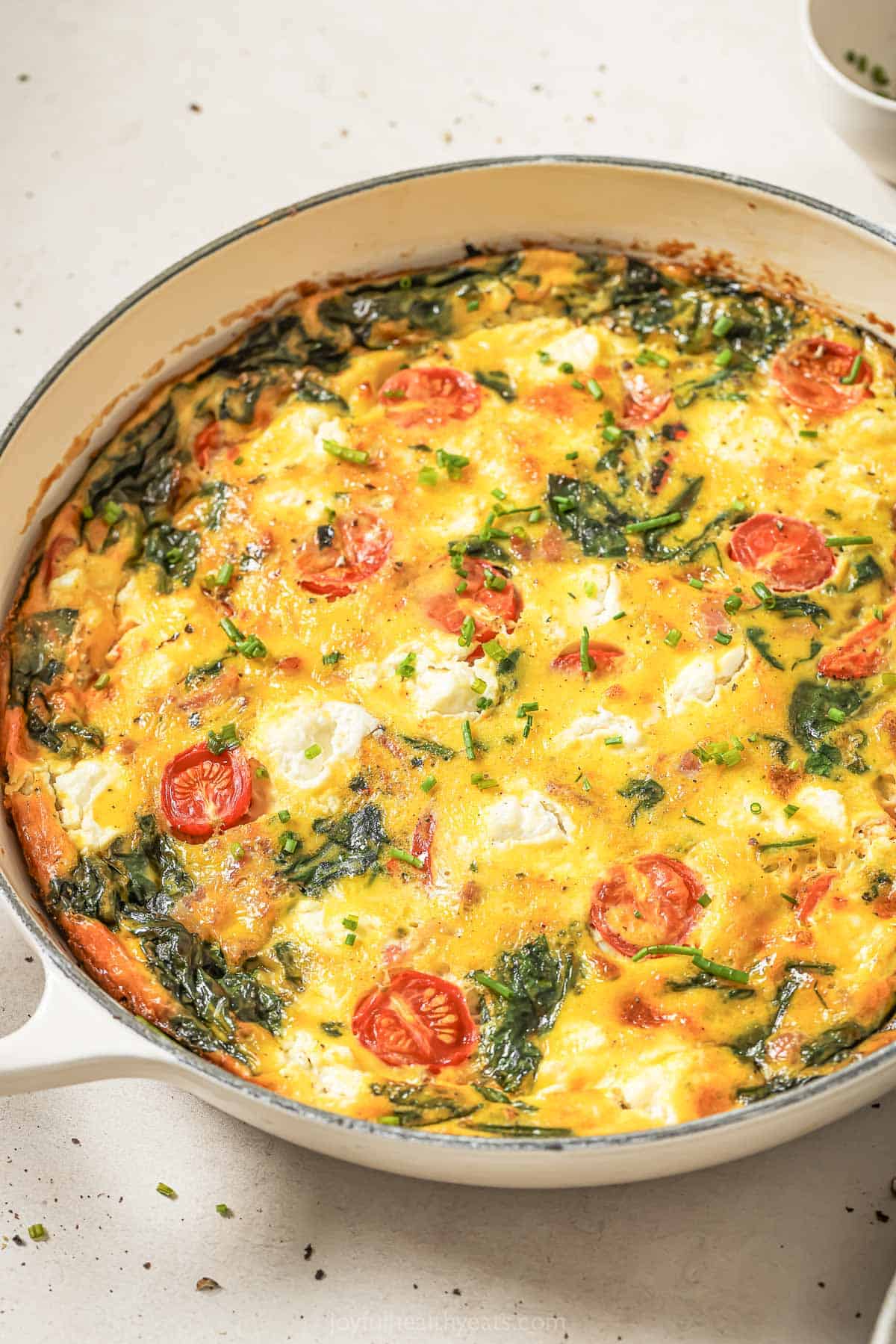 Whole cheesy bacon spinach frittata in skillet