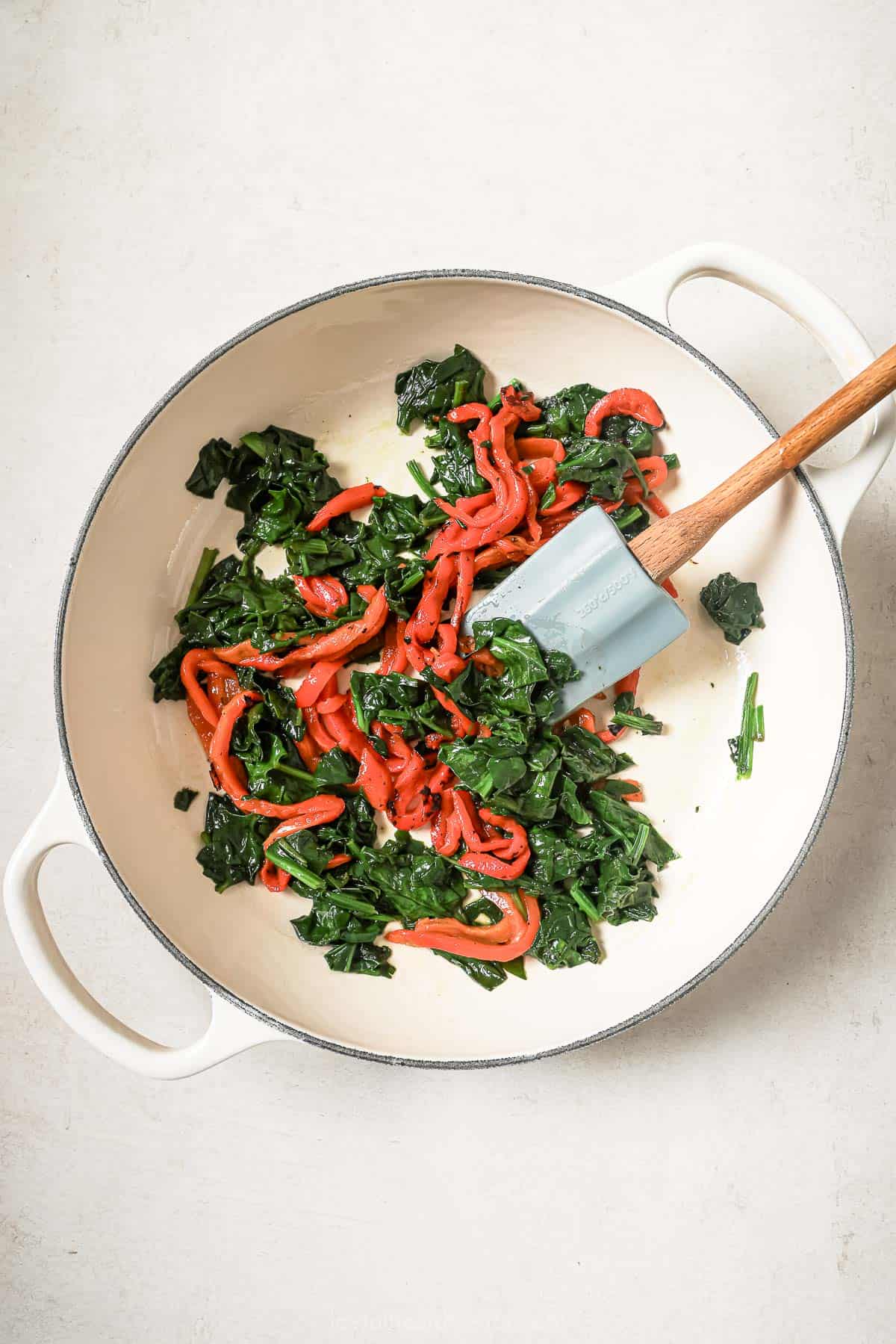 Spinach and roasted red peppers in skillet