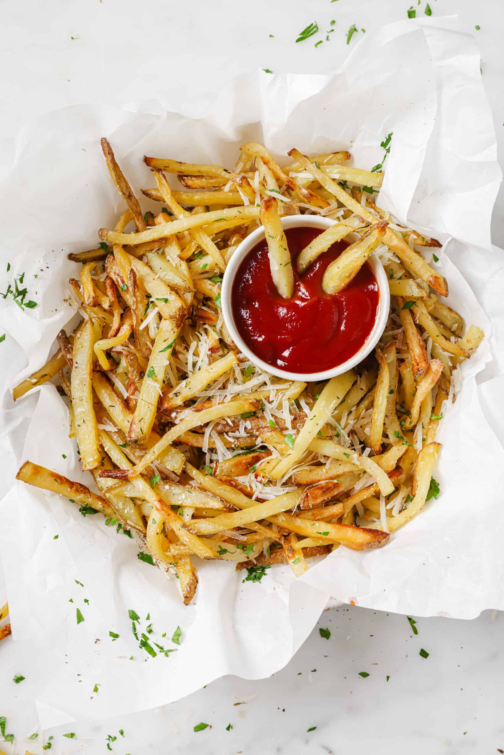 This baked garlic parmesan fries recipe is so good it might tempt you into eating the whole tray on your own. Good thing they're healthy! Garlic parmesan fries with a side of ketchup.